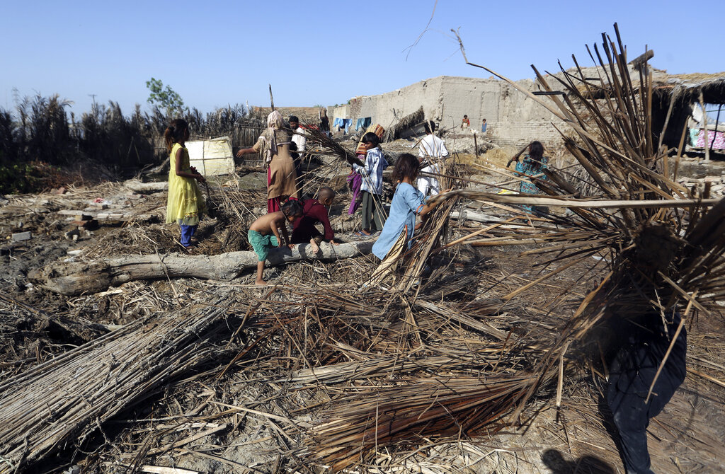 A family looks for salvageable belongings from their flooded home after heavy rain in Shikarpur district of Sindh province