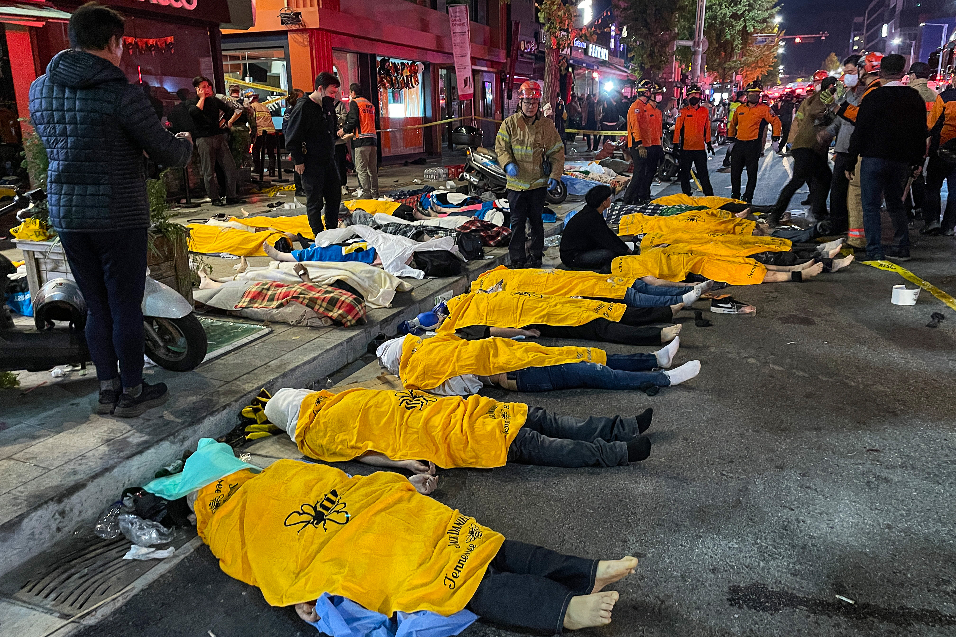 EDITORS NOTE: Graphic content / Bodies of victims, believed to have suffered cardiac arrest, are covered in the popular nightlife district of Itaewon in Seoul on October 30, 2022. - Dozens of people suffered from cardiac arrest in the South Korean capital Seoul, after thousands of people crowded into narrow streets in the city's Itaewon neighbourhood to celebrate Halloween, local officials said. (Photo by Yelim LEE / AFP)