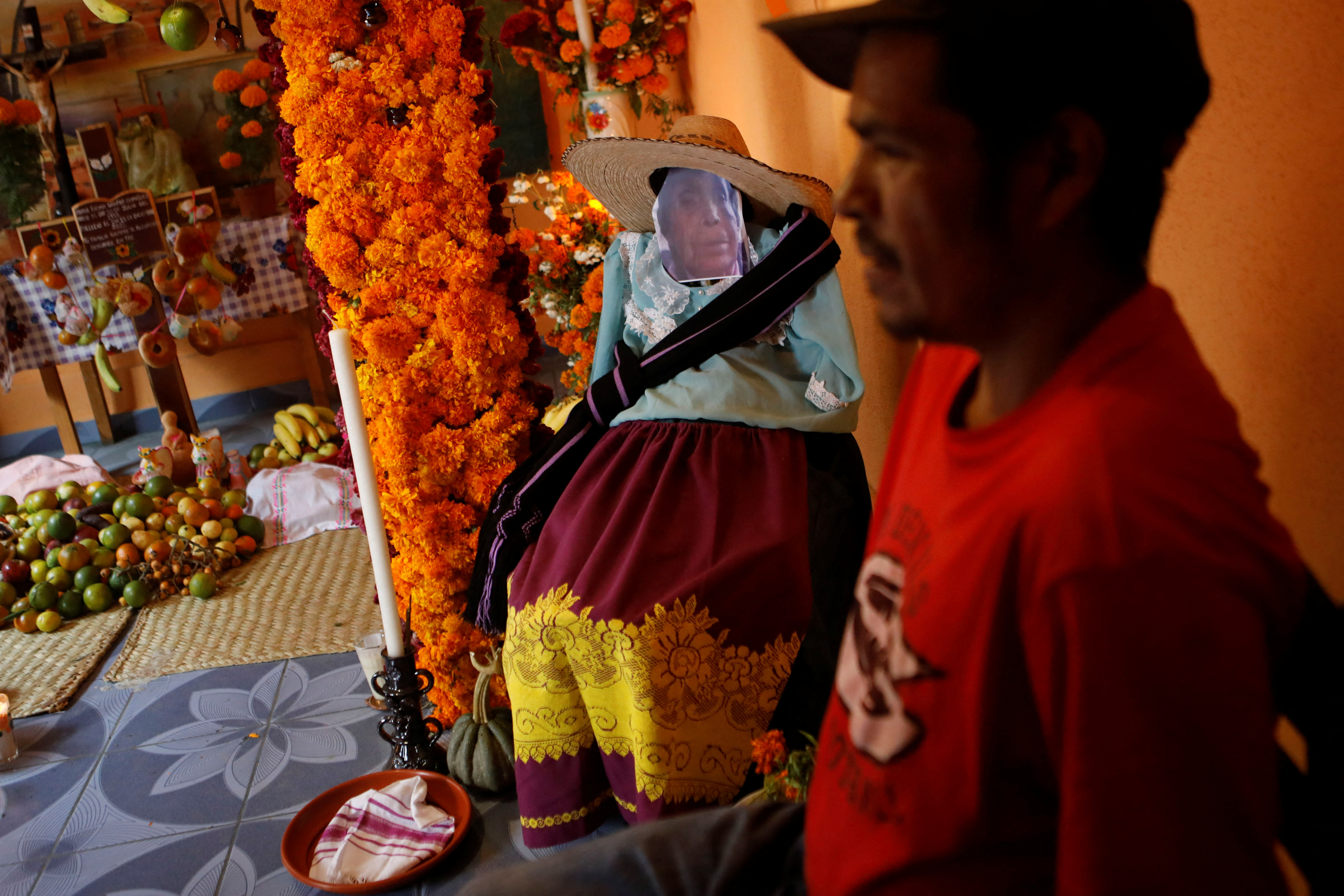 A man sits next to a portrait and clothes of a family member who died recently