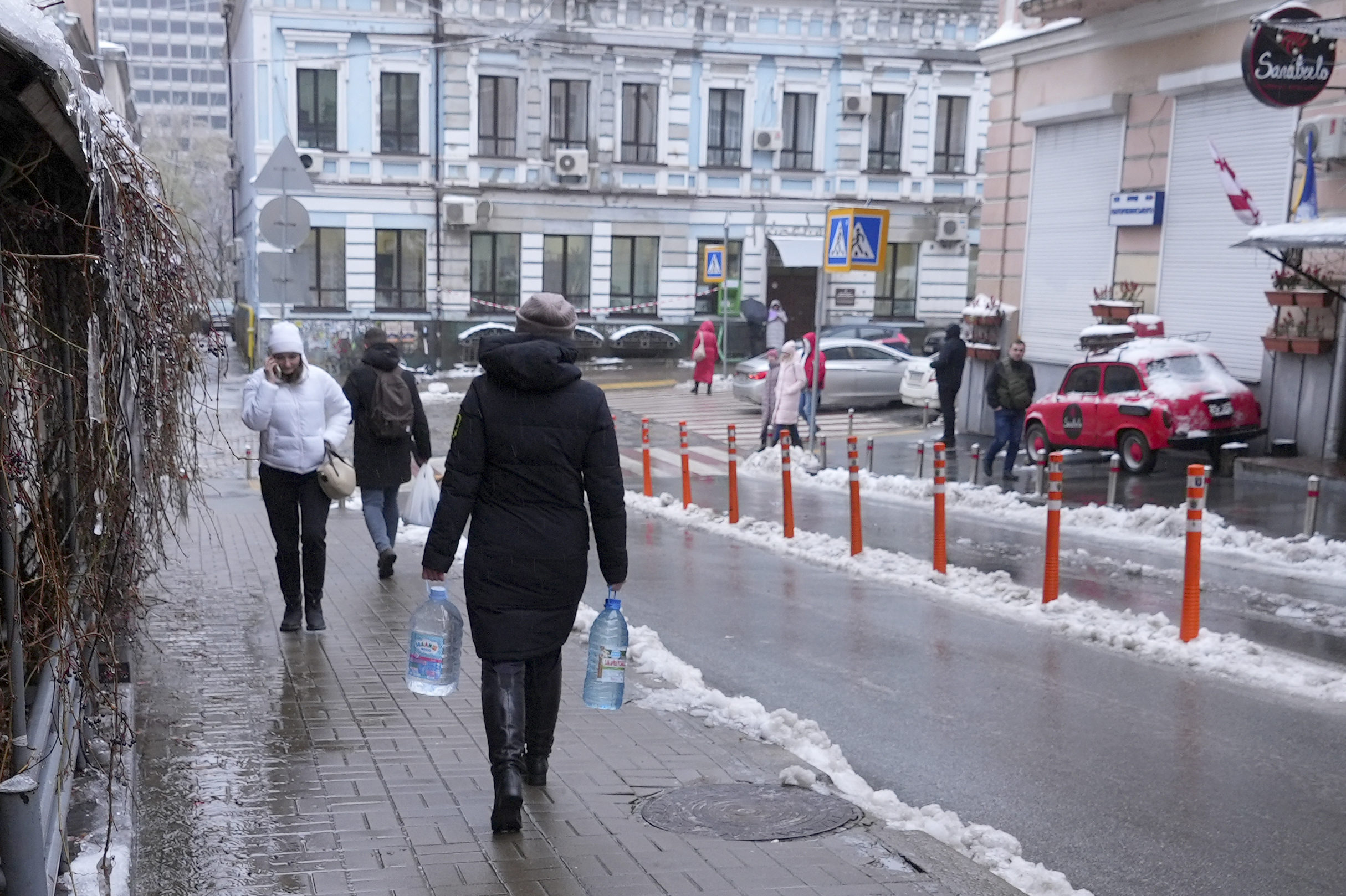 Kateryna Luchkina, a 31-year-old worker at Kyiv’s Department of Health, walks away after collecting rainwater from a drainpipe in Kyiv.