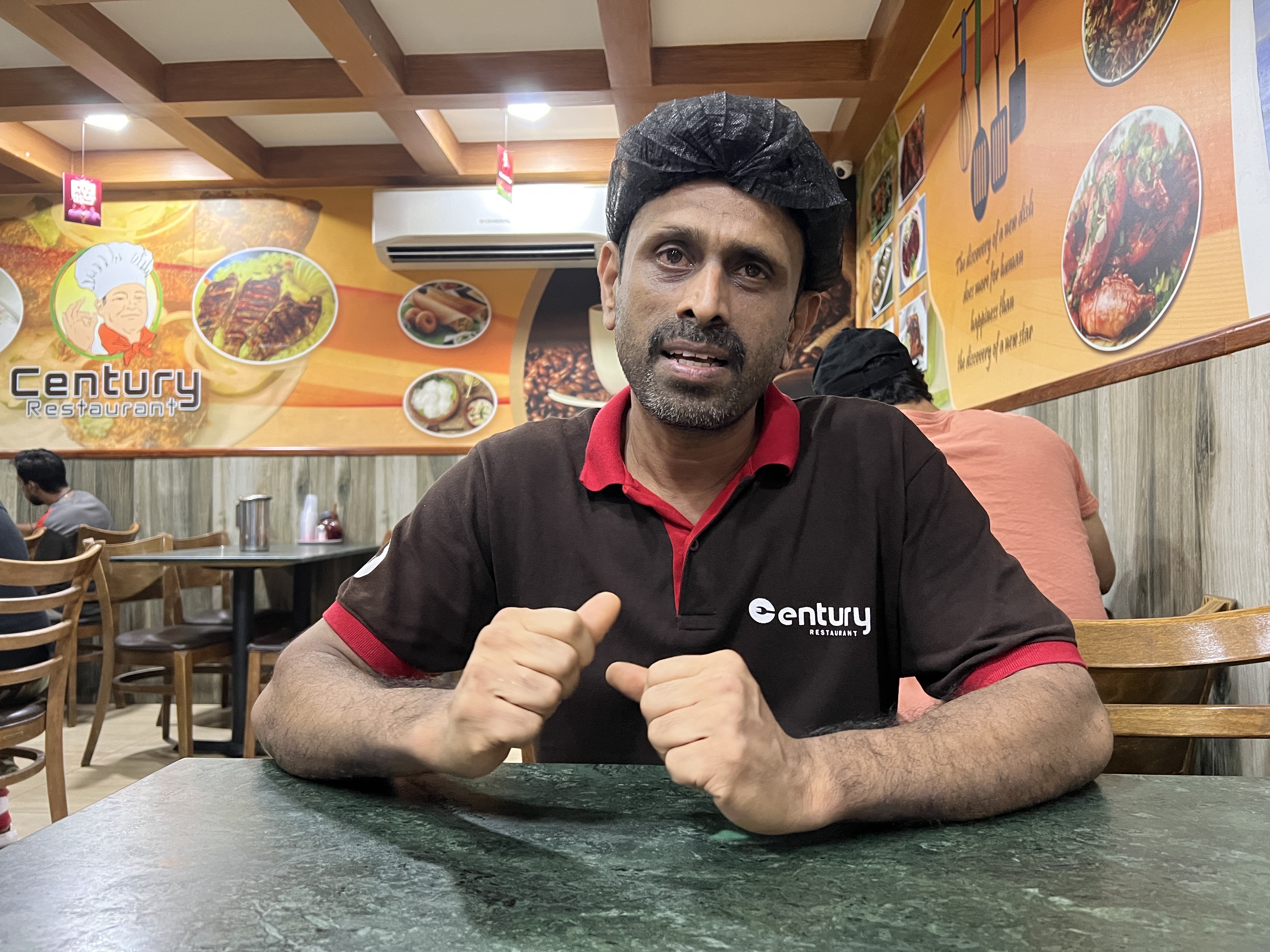 A photo of a waiter sitting in a chair at a restaurant.