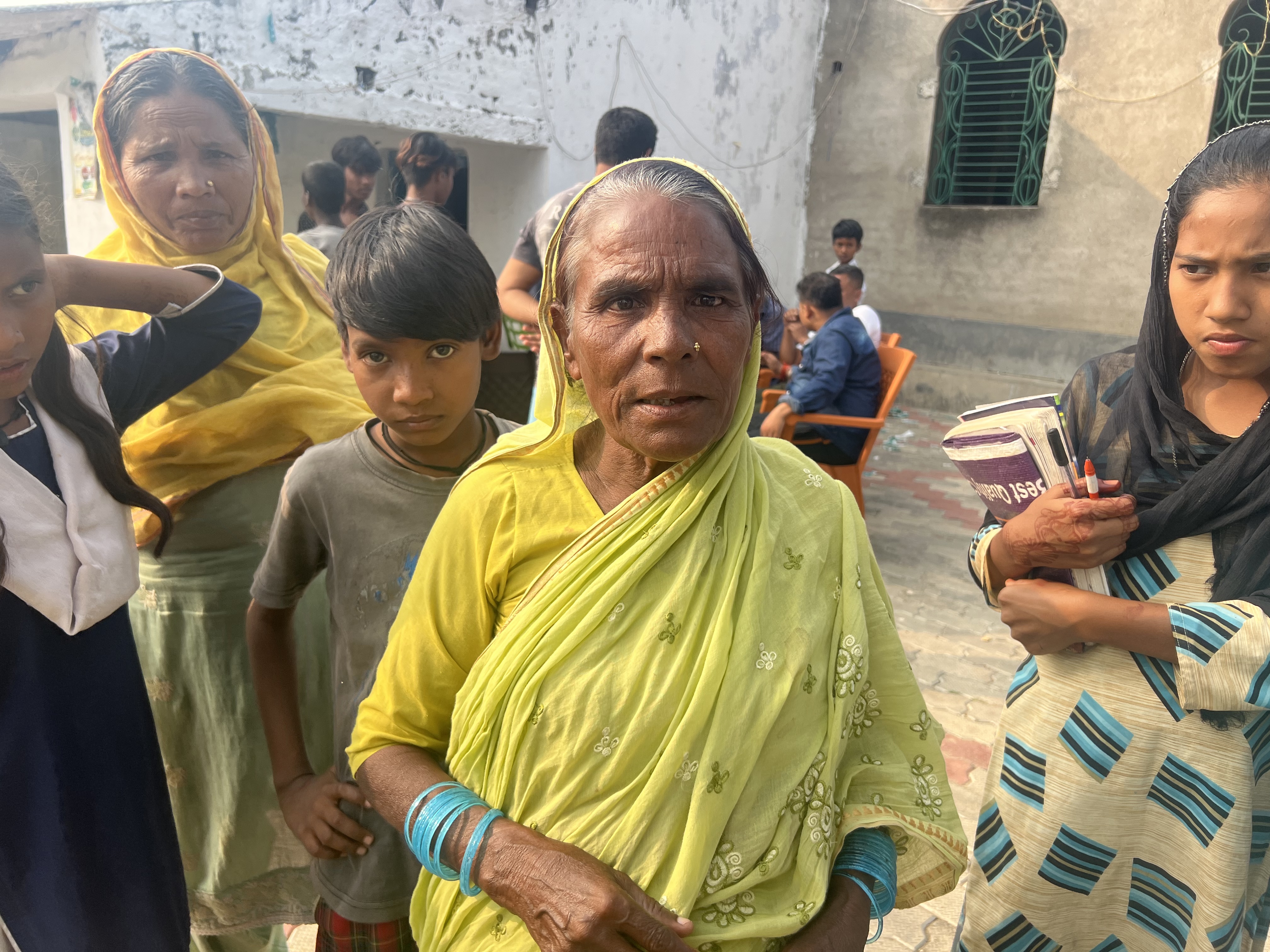 A photo of a woman with other women and children standing around her.