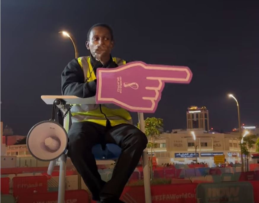 Abubakr Abbass on umpire chair, pointing a giant cardboard hand