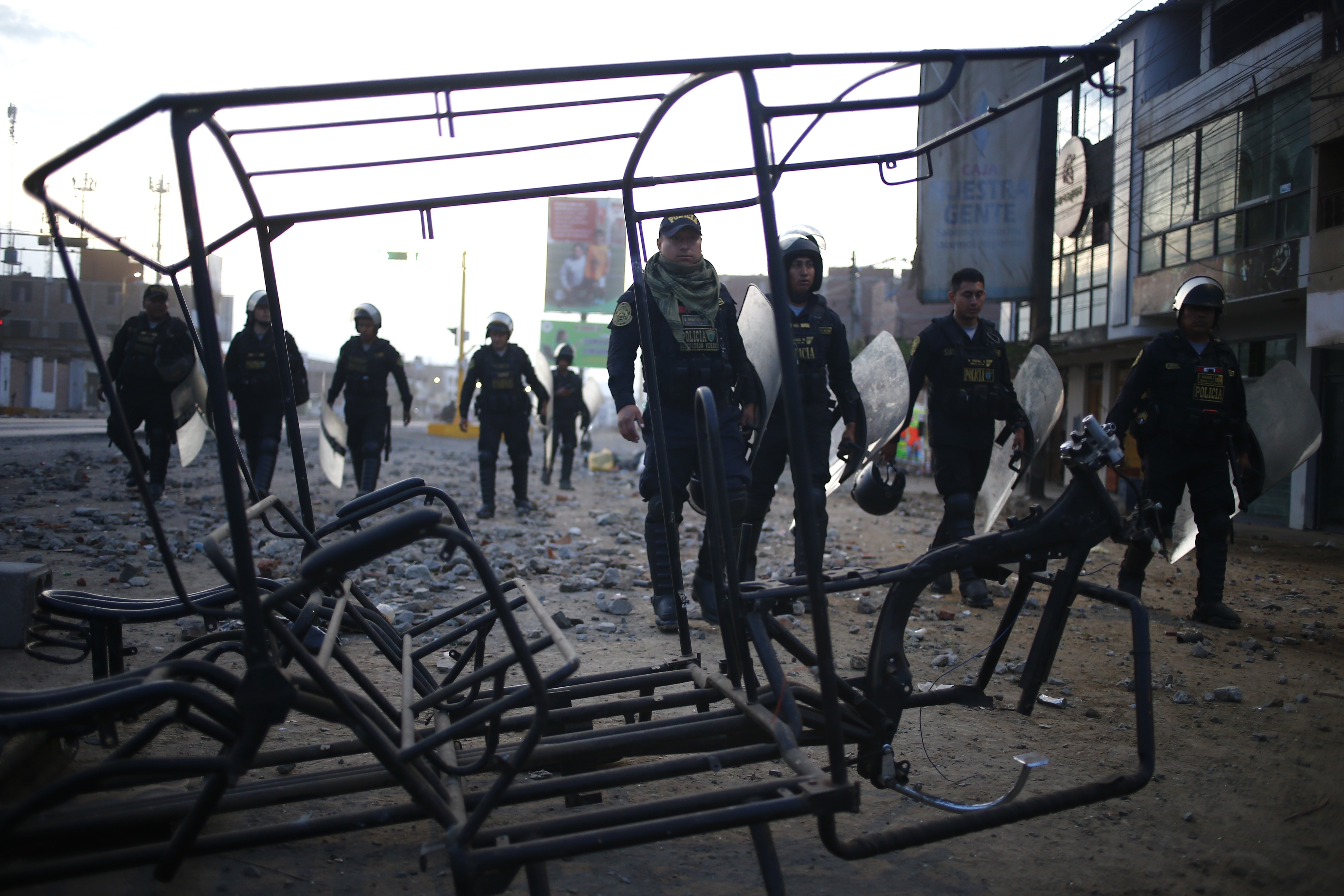 Police walk by a charred moto-taxi frame