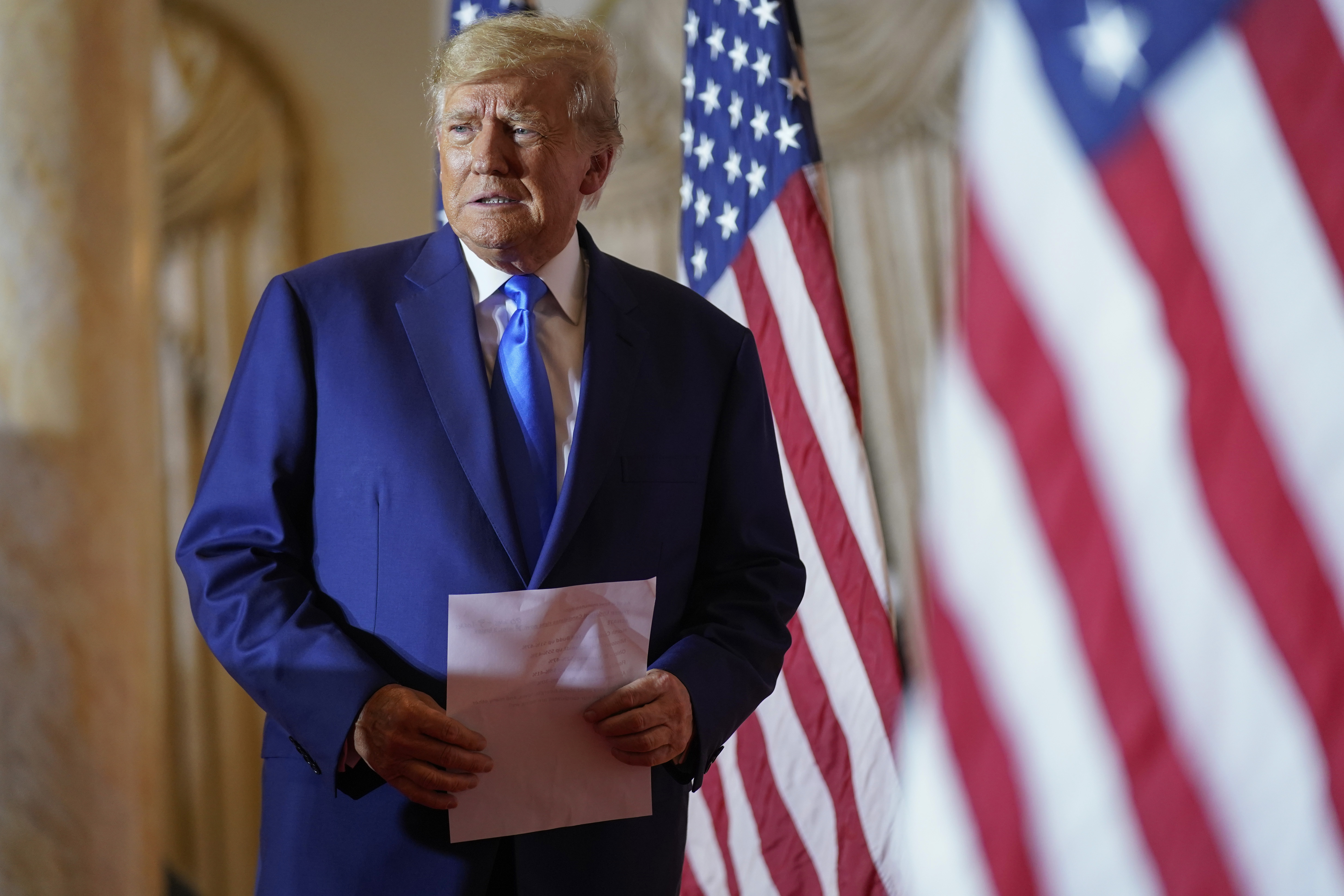 Former President Donald Trump arrives to speak at Mar-a-lago holding a piece of paper