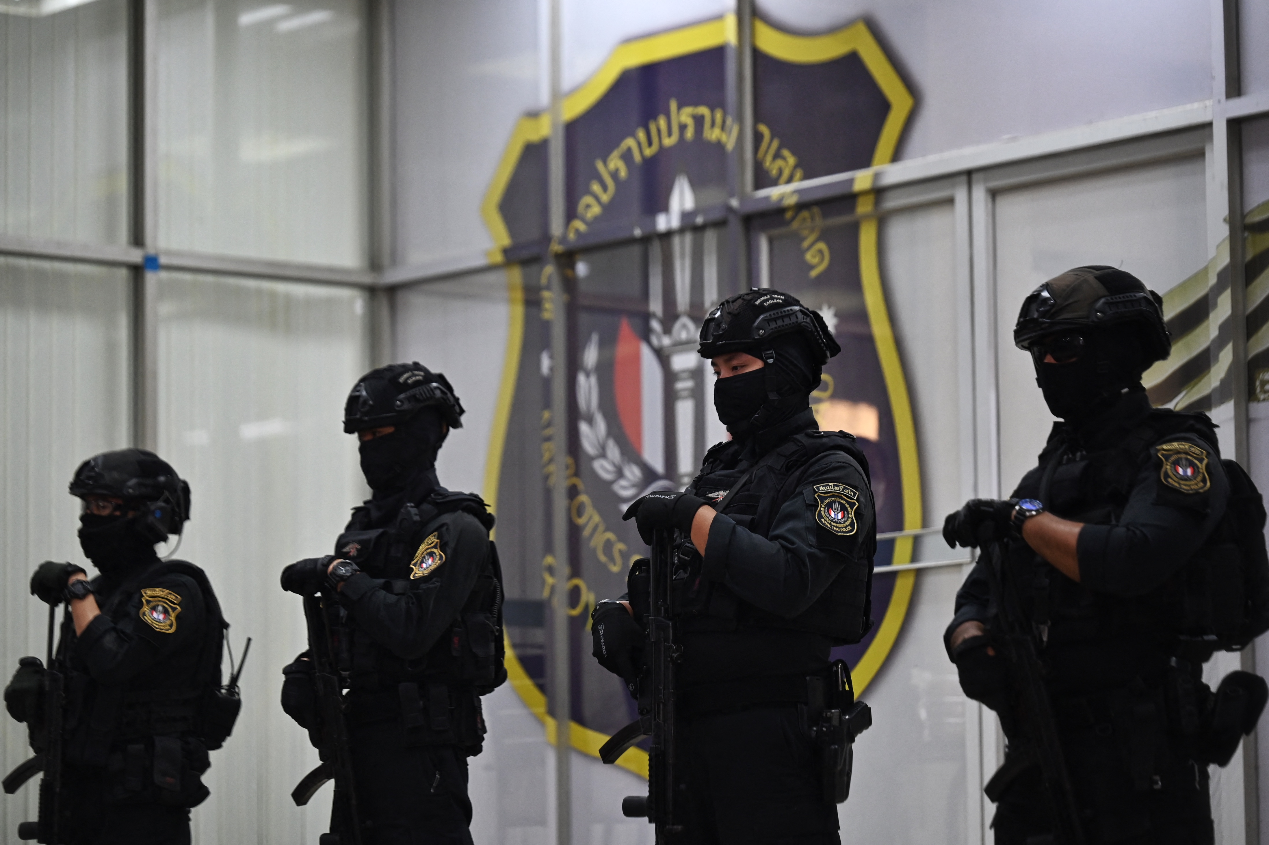 Personnel from the Narcotics Suppression Division stand guard as they secure packages of crystal methamphetamine before a press conference at the Narcotics Suppression Bureau in Bangkok on January 24, 2023. - More than a tonne of crystal meth was seized in less than a week, Thai police said Tuesday, after officers discovered some illicit stimulants hidden in tea and coffee bags. (Photo by Lillian SUWANRUMPHA / AFP)