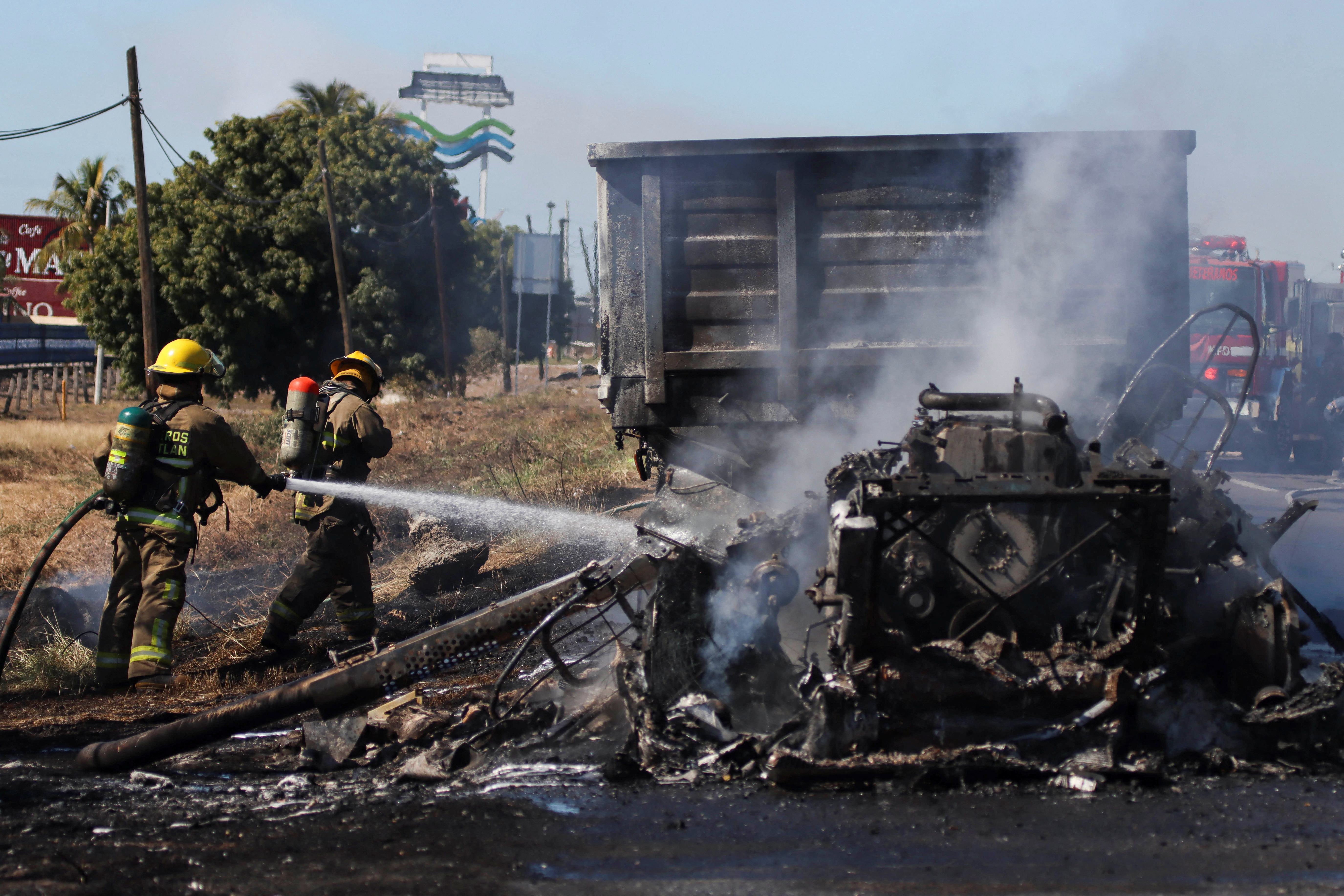 Firefighters extinguish a vehicle set ablaze by drug cartel members in Mazatlan, Mexico, on January 5, 2023