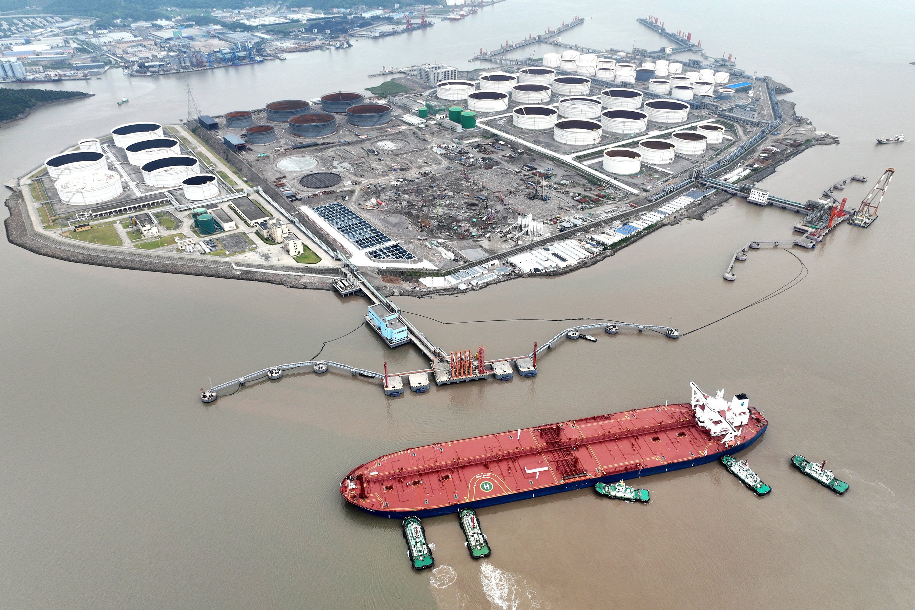 An aerial view shows tugboats helping a crude oil tanker to berth at an oil terminal, off Waidiao Island in Zhoushan, Zhejiang province, China.