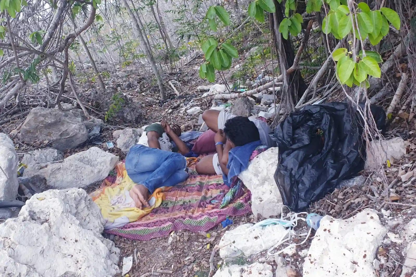 Mohammad Shofigul Islam and Mohammad Kaium, lying on the ground under some brush, have stitched their lips shut to protest their detention on the island nation of Nauru for almost a decade. {Courtesy of Mohammad Shofiqul)