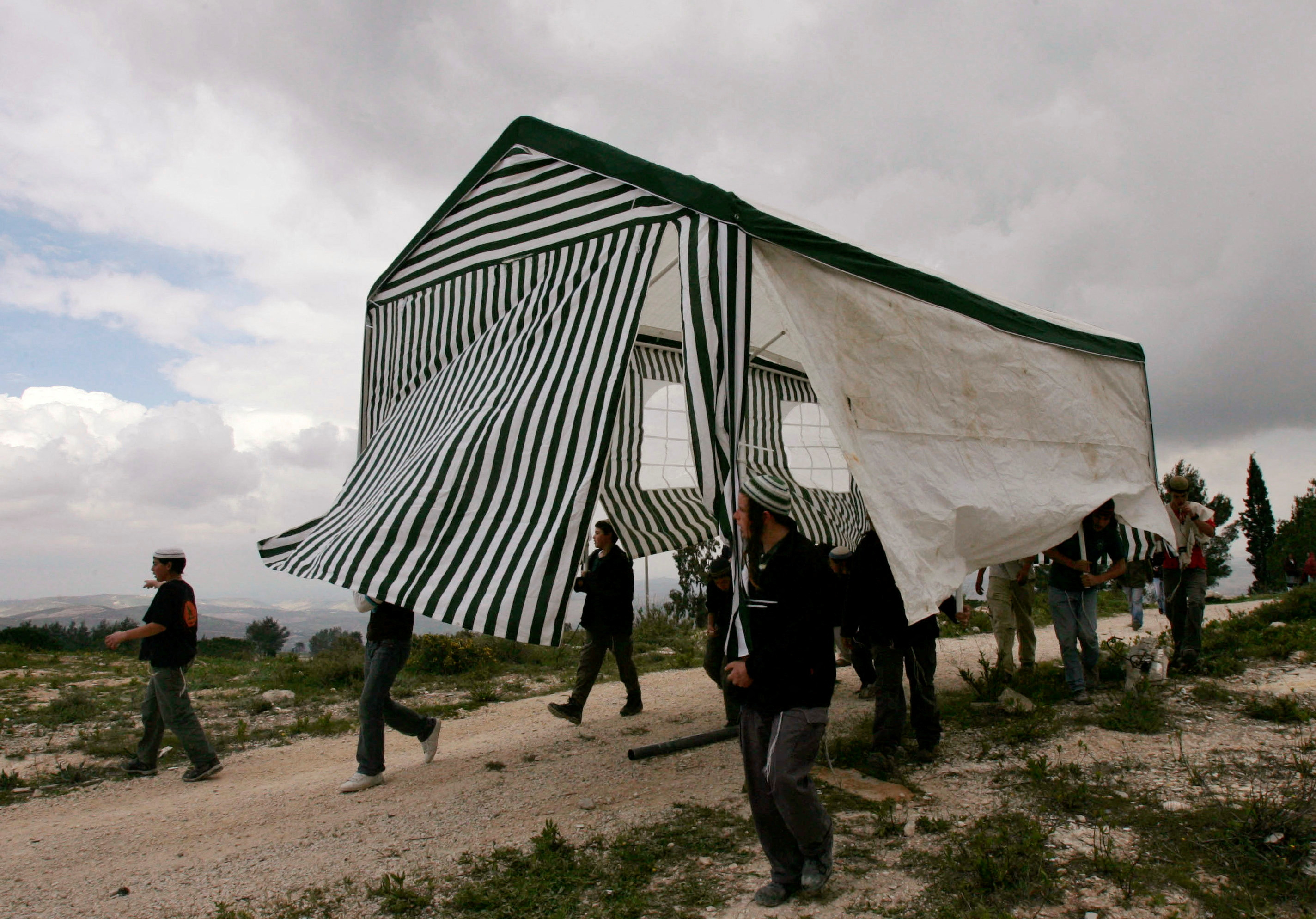Israeli activists carry a tent in the abandoned Jewish settlement of Homesh, in the northern West Bank, March 27, 2007.