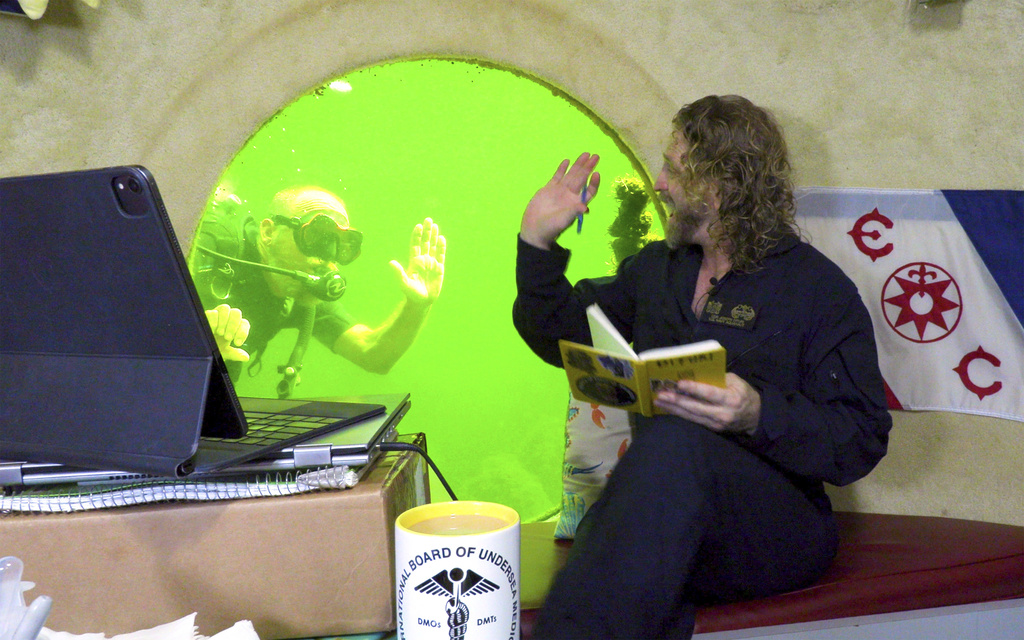 Researcher waves to a scuba diver from his window