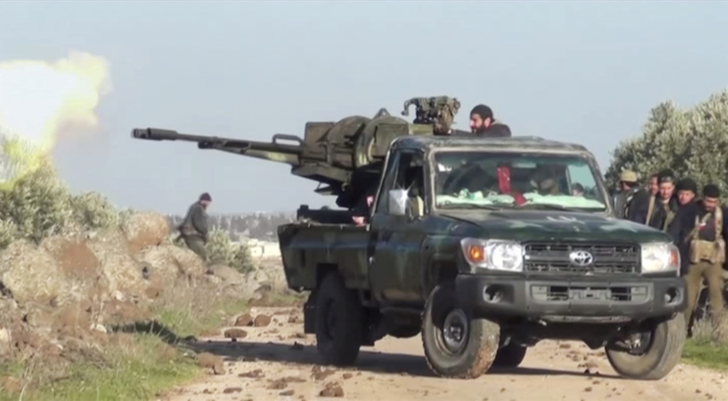 A still image taken from a video obtained by Reuters and shot on March 2, 2020, shows Syrian army soldiers firing a weapon as they advance on the town of Kfar Nabl, Syria. Reuters TV/via REUTERS