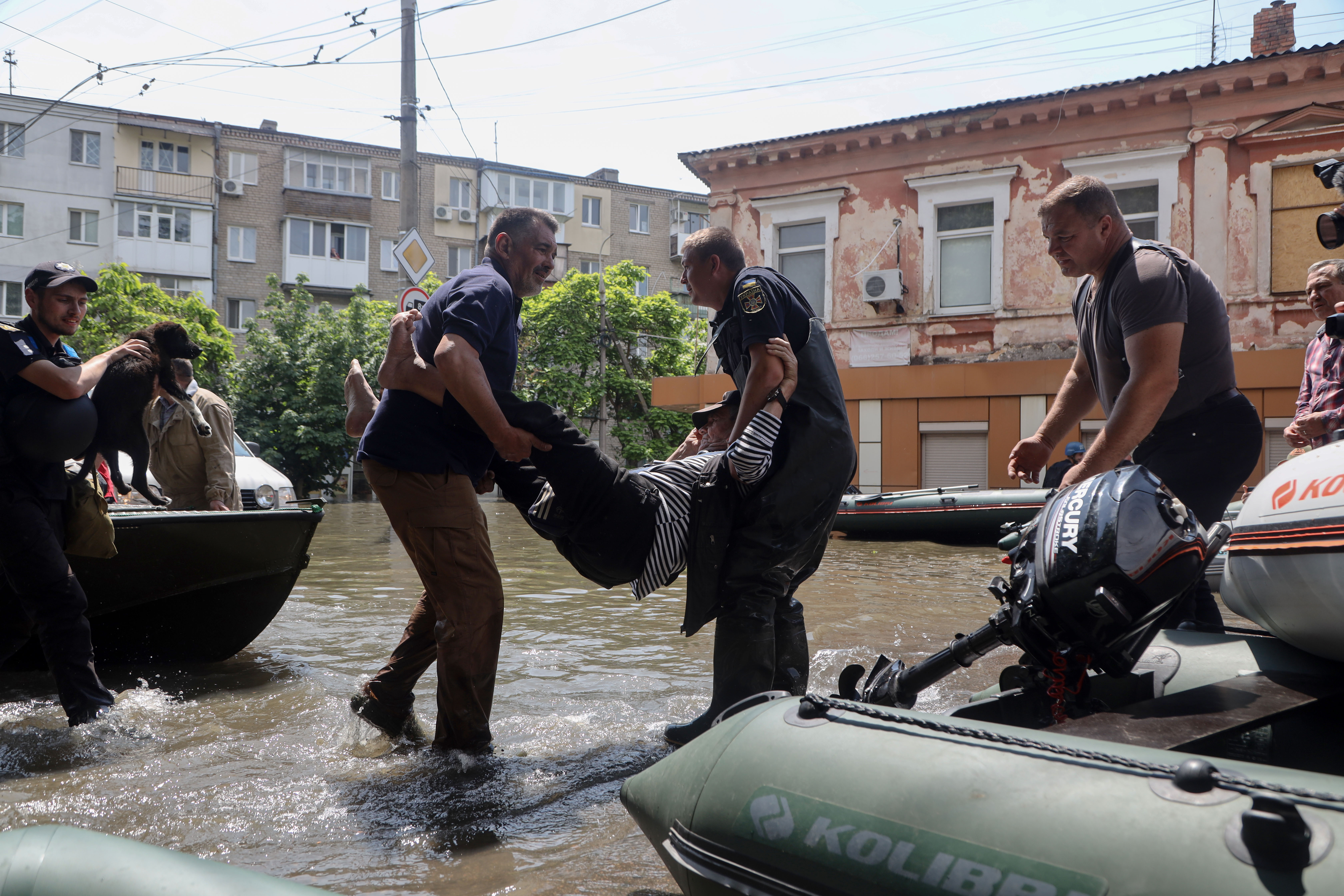 Ukrainian security forces carry an elderly resident to a boat during an evacuation from a flooded area in Kherson on June 7, 2023, following damages sustained at Kakhovka hydroelectric power plant dam.