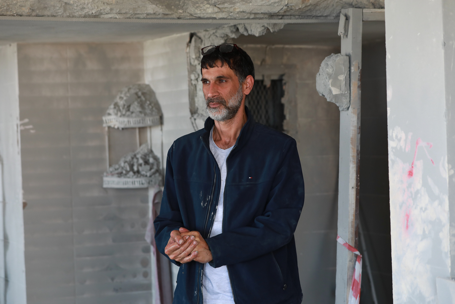 Hani stands, unable to speak, in the middle of his destroyed home