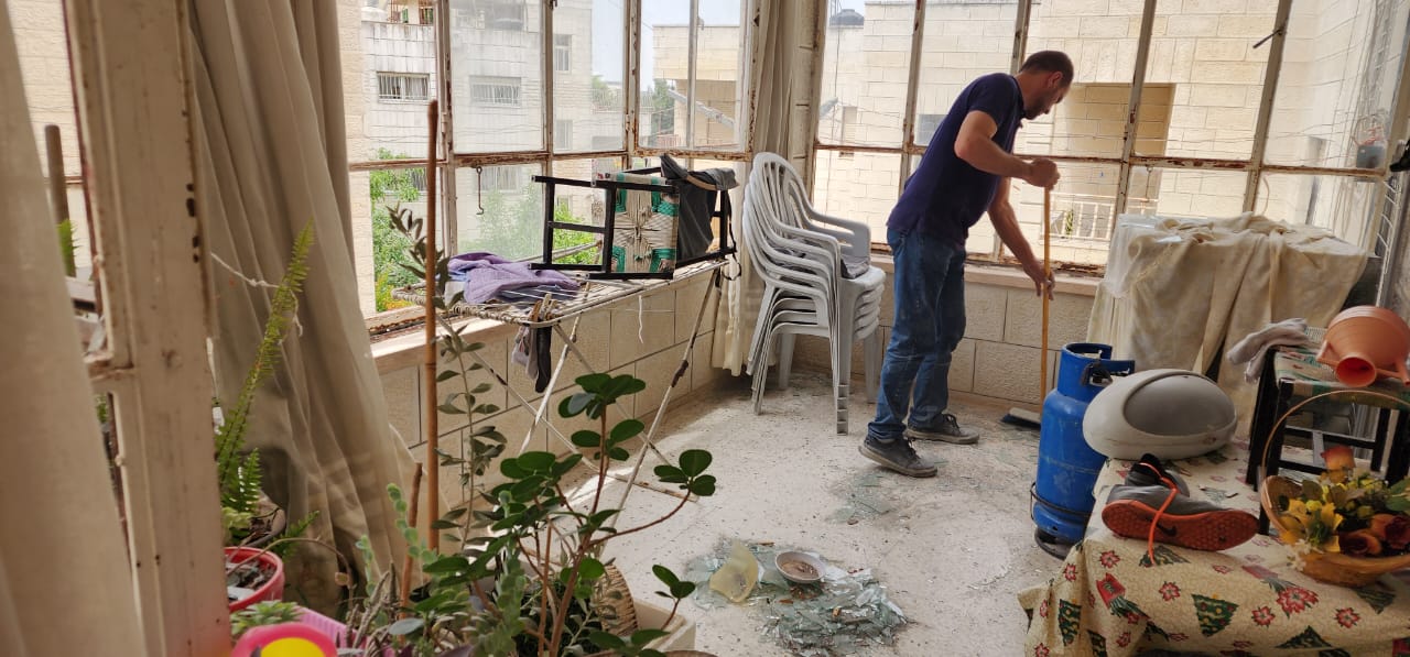 Ibrahim Musa sweeps up shattered glass from the windows in his home that were blown out by the force of an Israeli demolition operation that destroyed the adjacent Faroukh family home on June 8, 2023