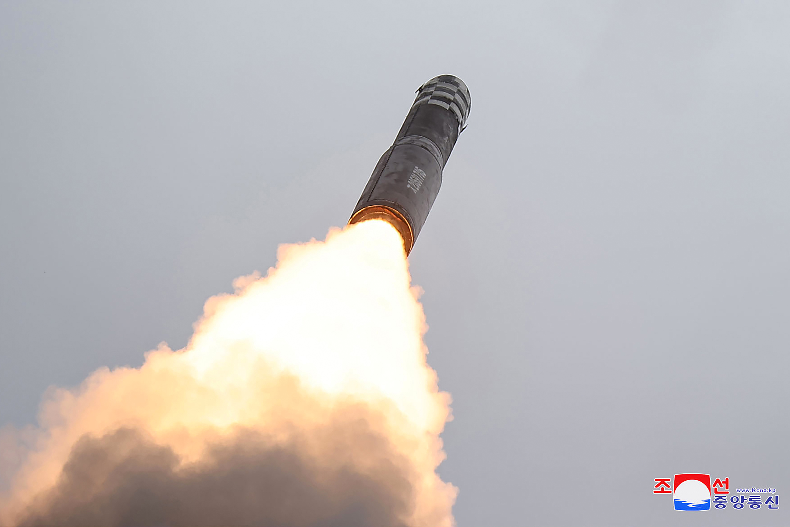 A closer view of the Hwasong 18 as it climbs away from the launch site in a cloud of smoke and flame.