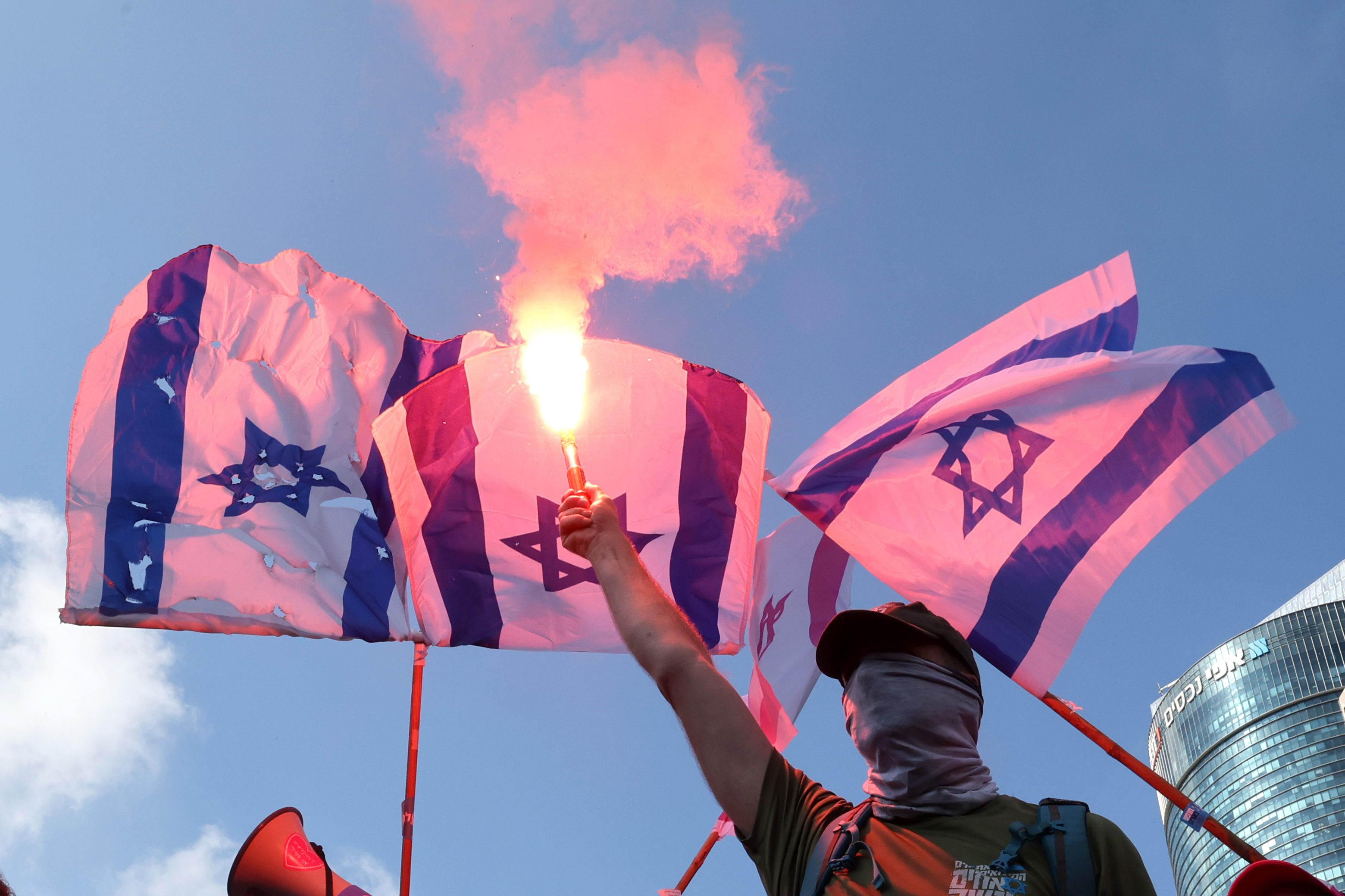 Demonstrators use flares as they stage a 'day of resistance' to protest the Israeli government's judicial overhaul bill, in Tel Aviv on July 18, 2023. - The proposals have divided the nation and triggered one of the biggest protest movements in Israel's history since being unveiled in January by the hard-right government of Prime Minister Benjamin Netanyahu. (Photo by JACK GUEZ / AFP)