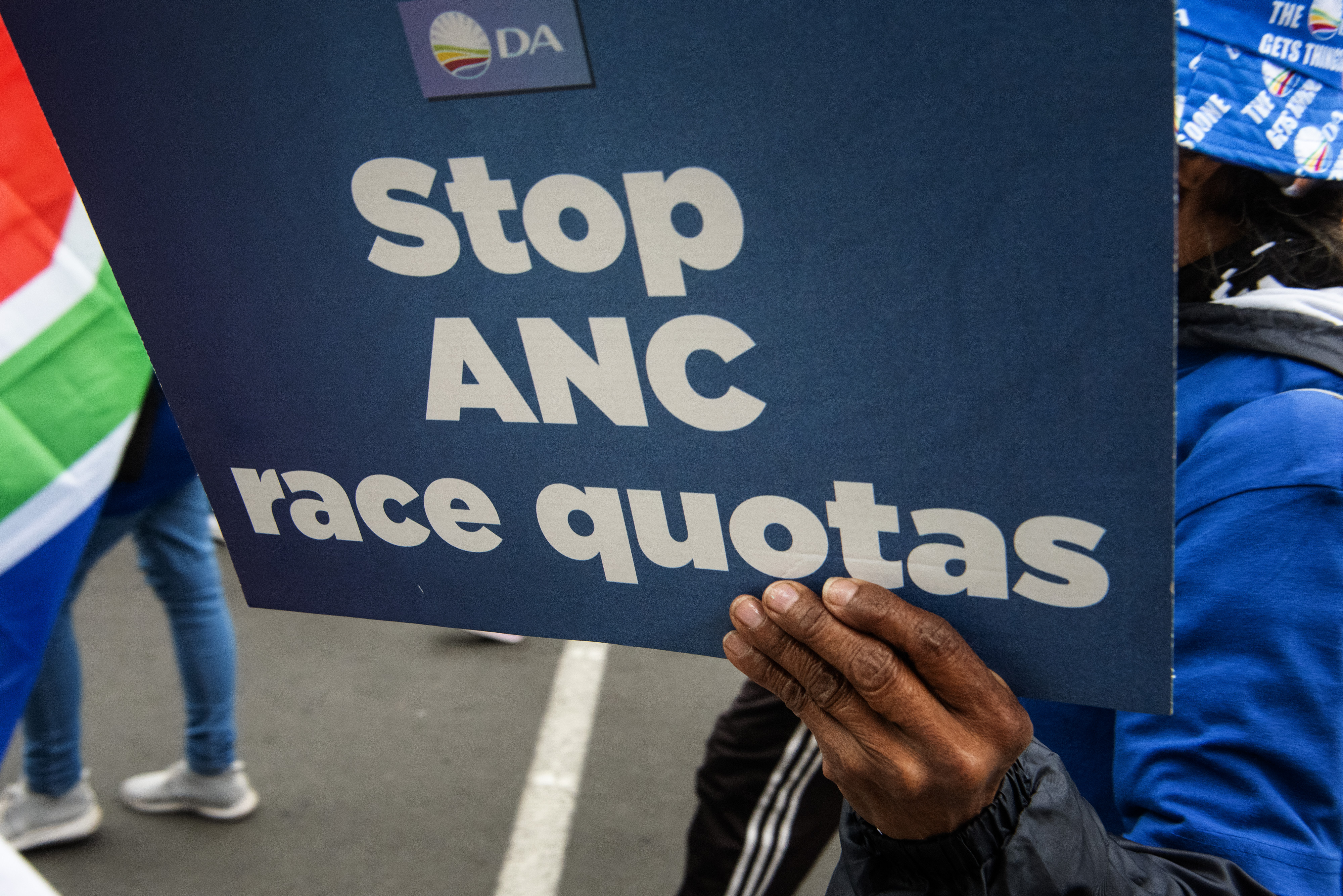 A person holds a placard as supporters of the Democratic Alliance (DA), South Africa’s main opposition party, march in Cape Town to protest against the new proposal for employment quotas, on July 26, 2023