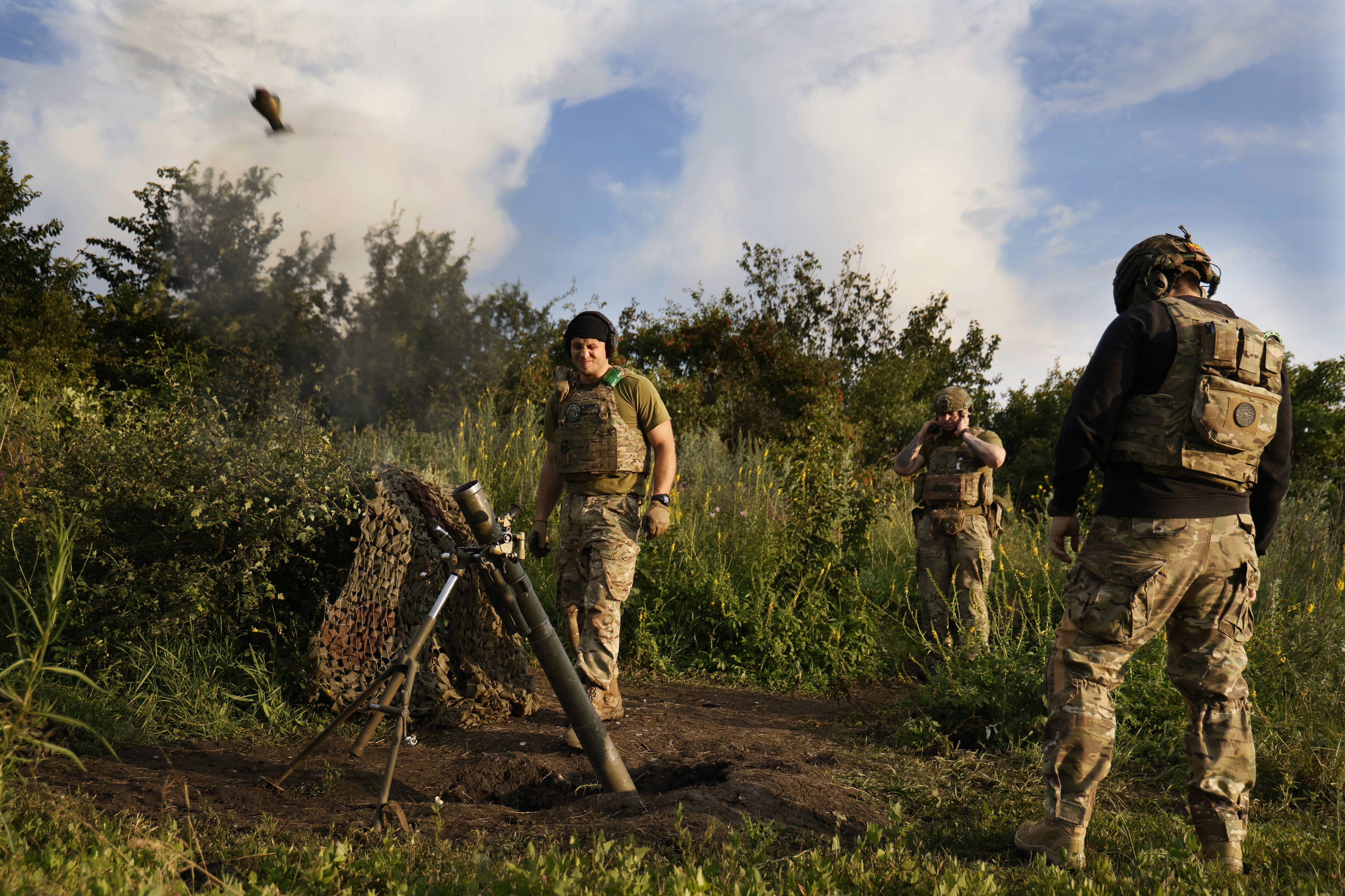 Three Ukrainian soldiers firing mortar rounds towards the Russians on the front line near Bakhmut. The mortar can be seen rising into the air.