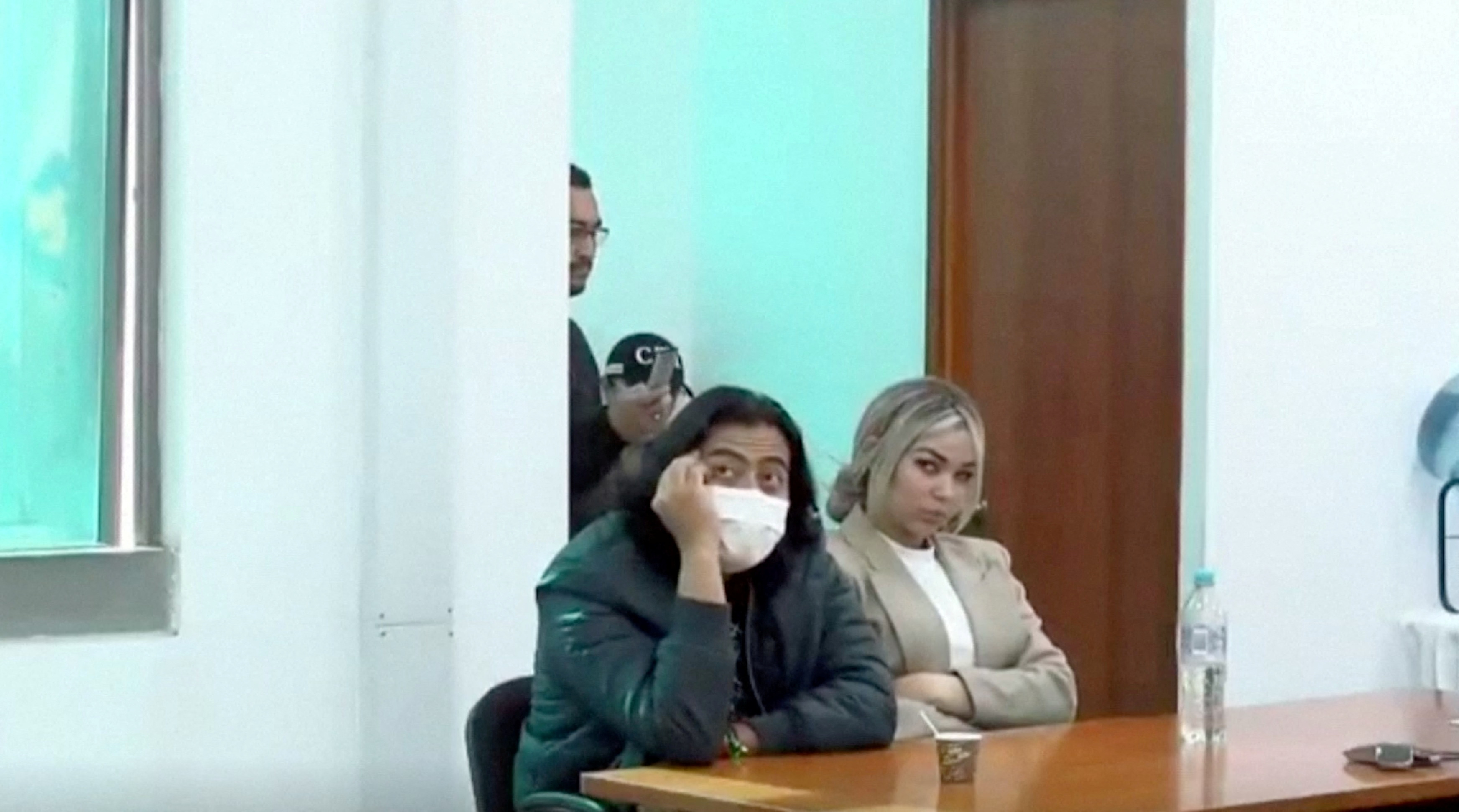 A man, Nicolas Petro, sits at a table with his head propped on his hand, wearing a face mask.