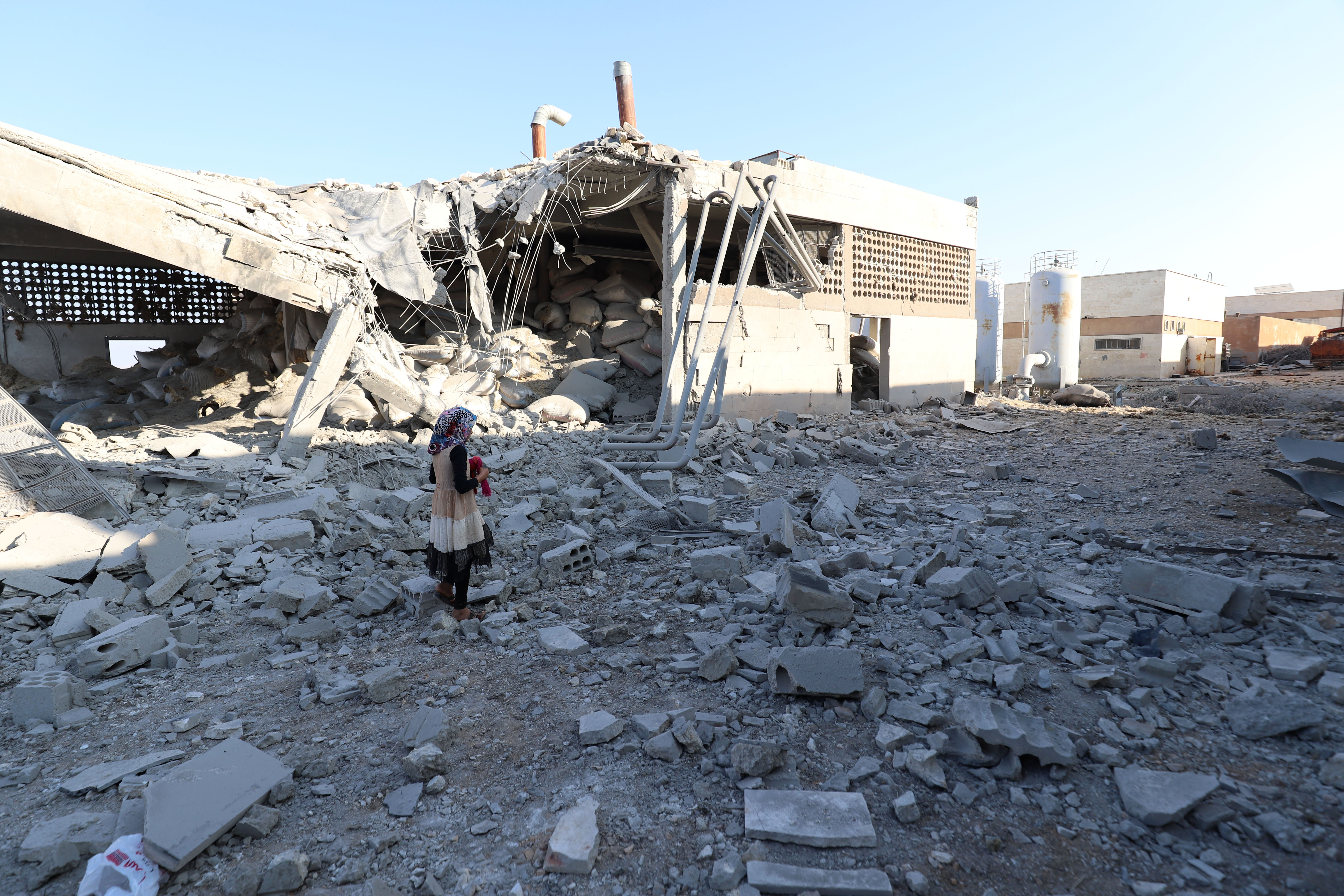 A girl stands amidst debris after at least two civilians were killed when Russian air strikes hit an abandoned water pumping station in Syria's rebel-held northwest