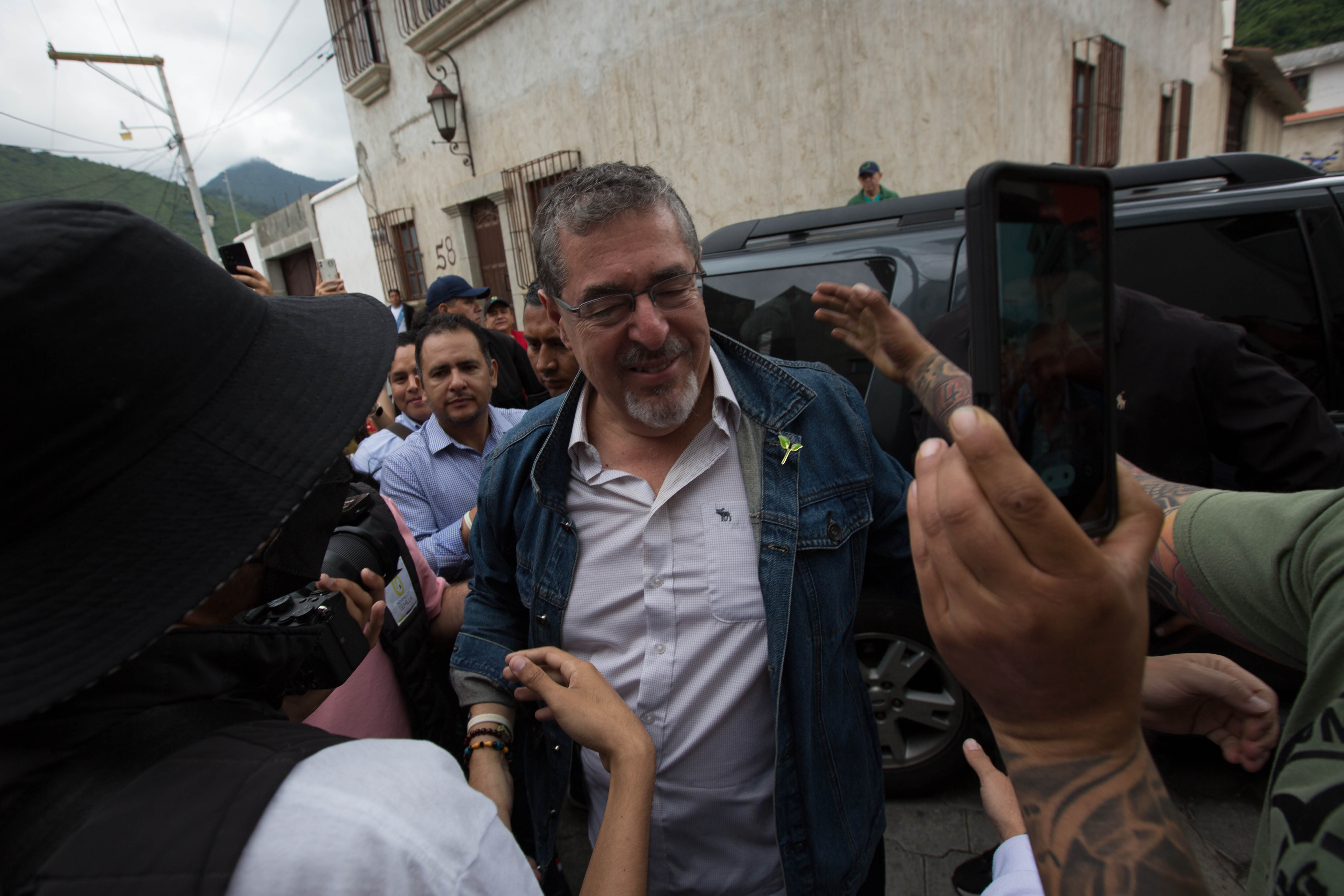 Supporters surround Bernardo Arevalo on the street, holding up cellphones to take pictures.