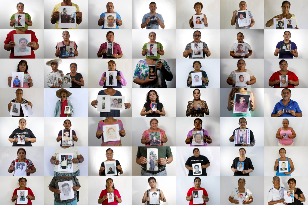 People hold photographs of missing relatives