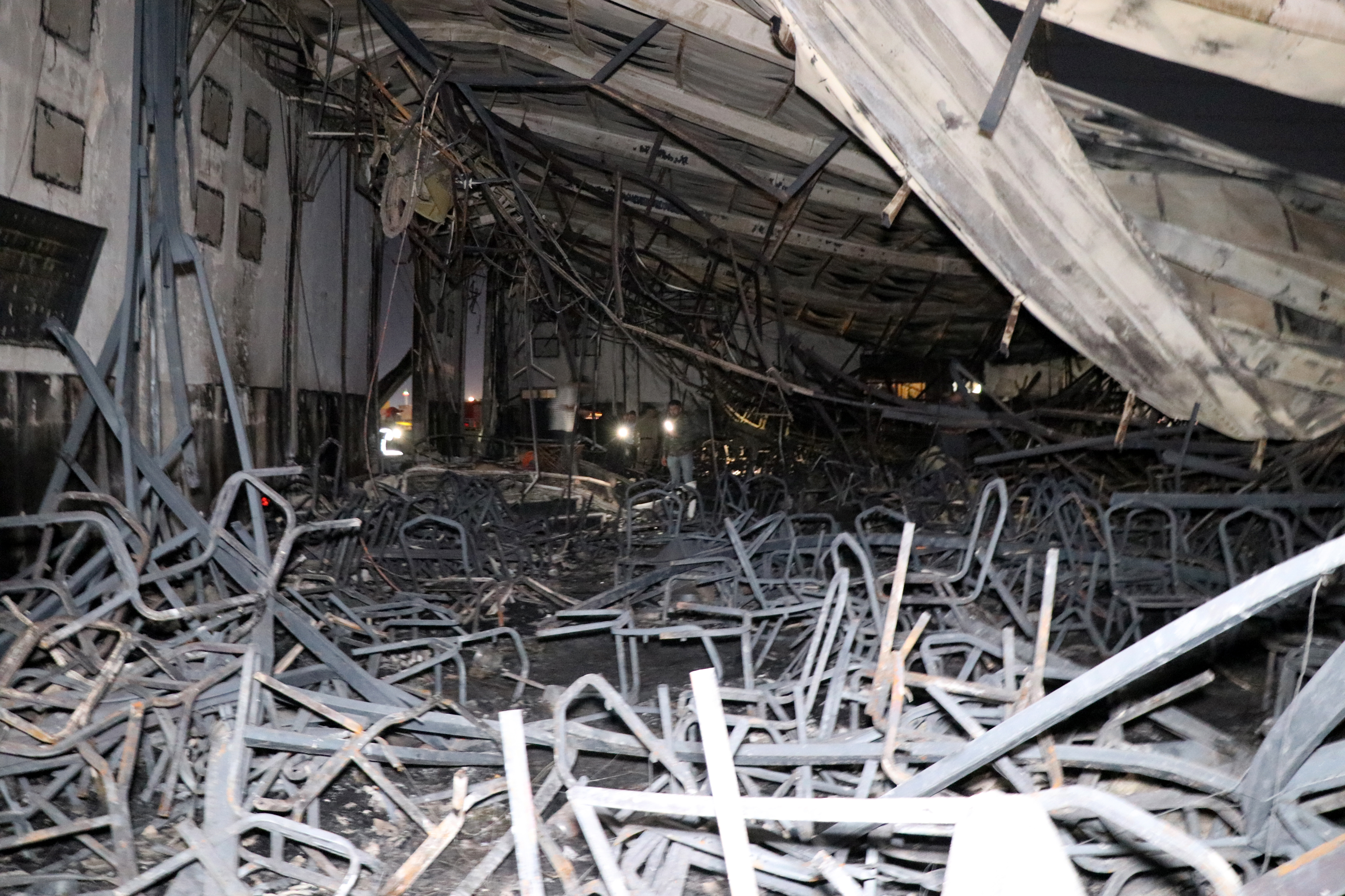 Iraqi security men inspect the scene of the wedding hall fire in Hamdaniya