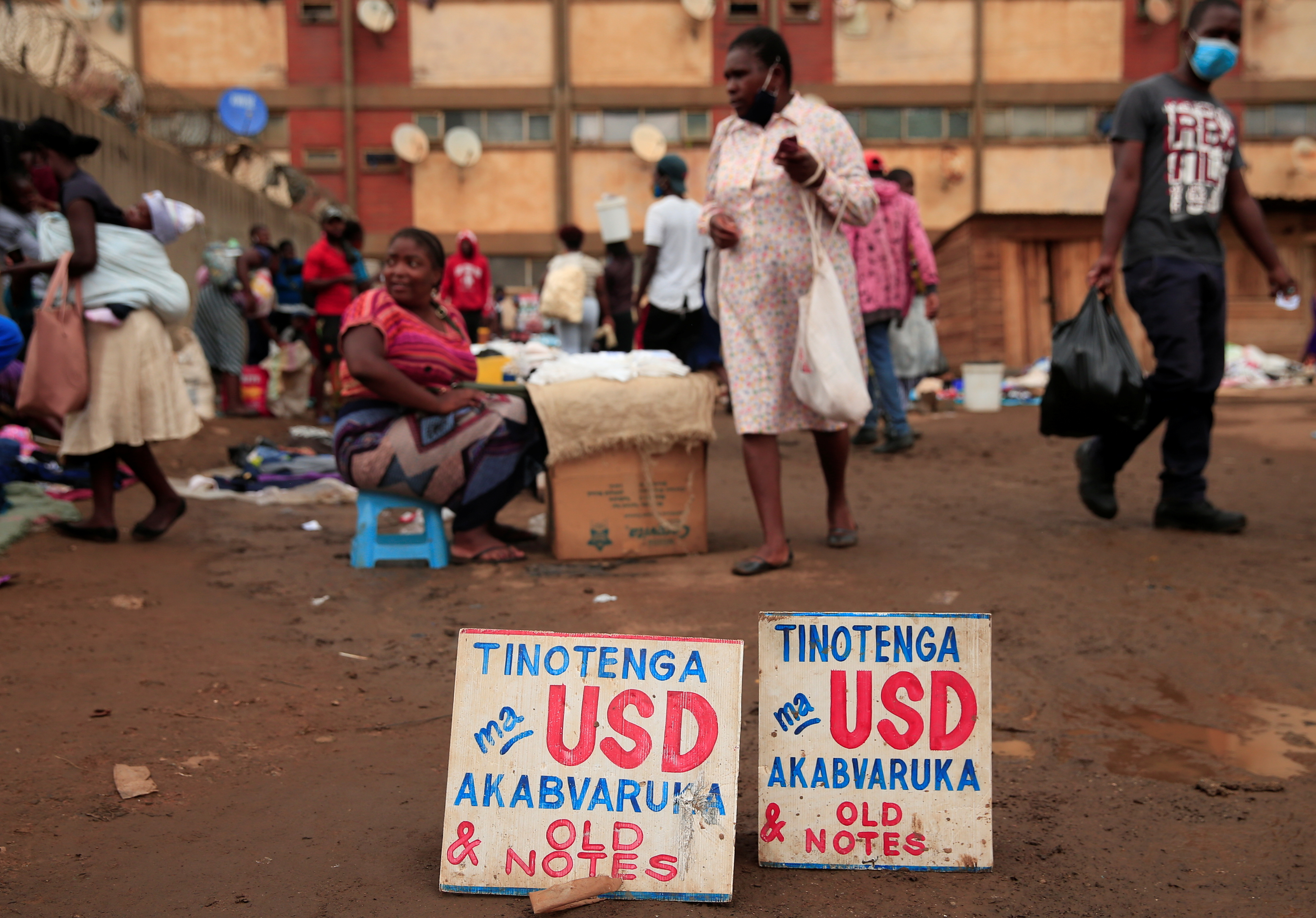 People walk past a money-changers sign at a market in Harare. US dollars are the preferred currency in Zimbabwe