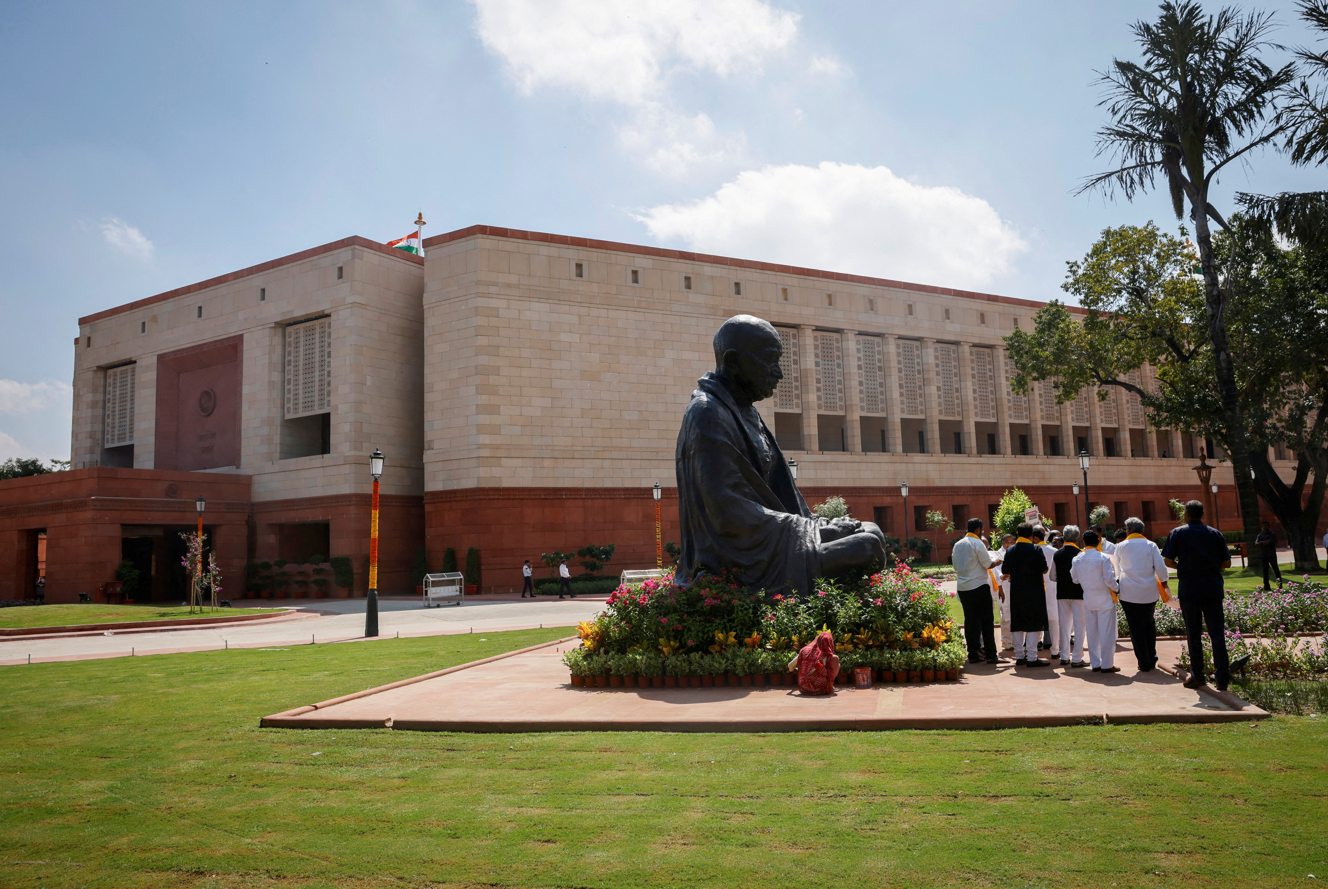 A statue of Mahatma Gandhi stands next to India’s new parliament building