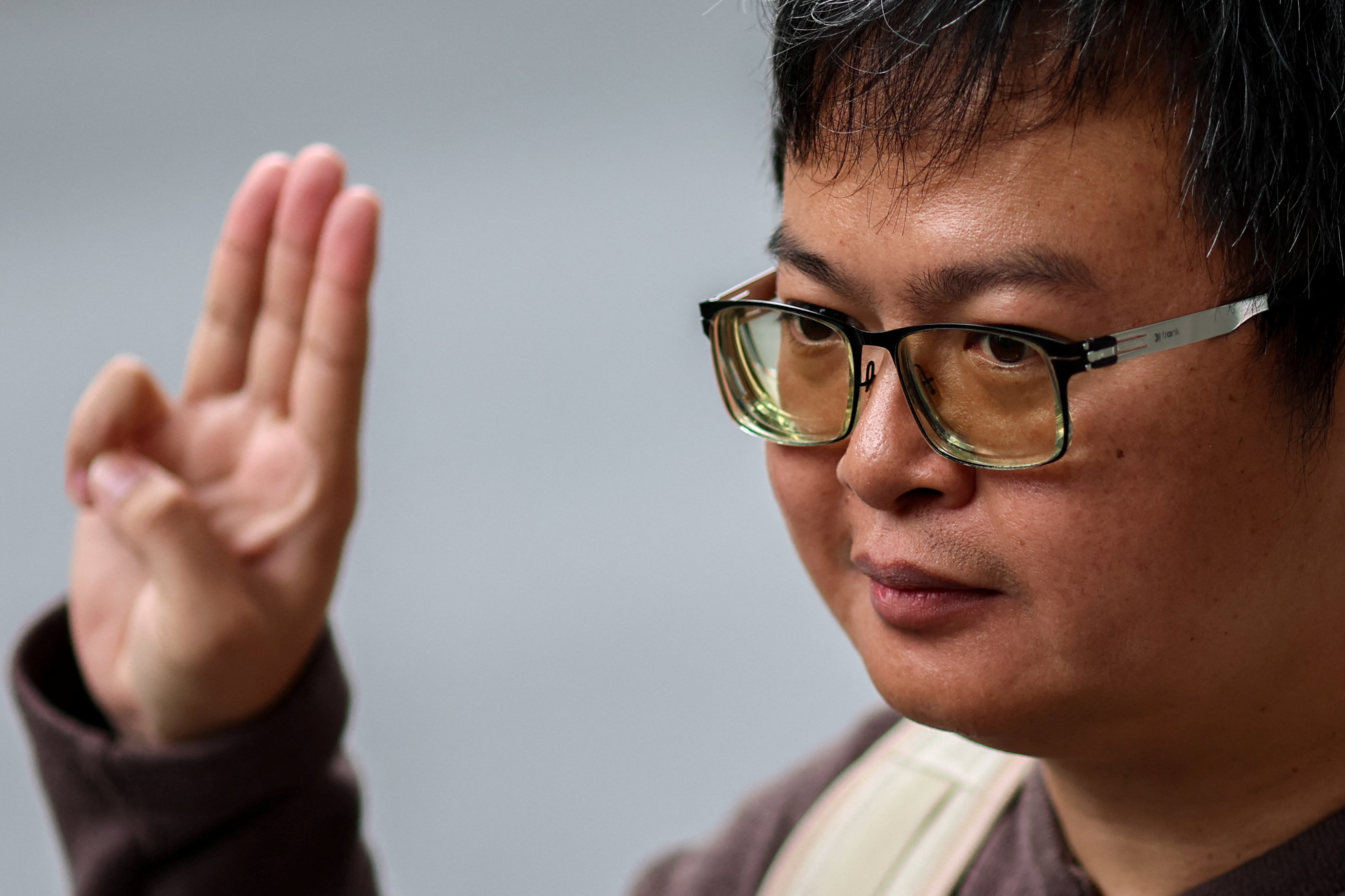A close up picture of activist Anon Nampa. He is doing the three fingered salute
