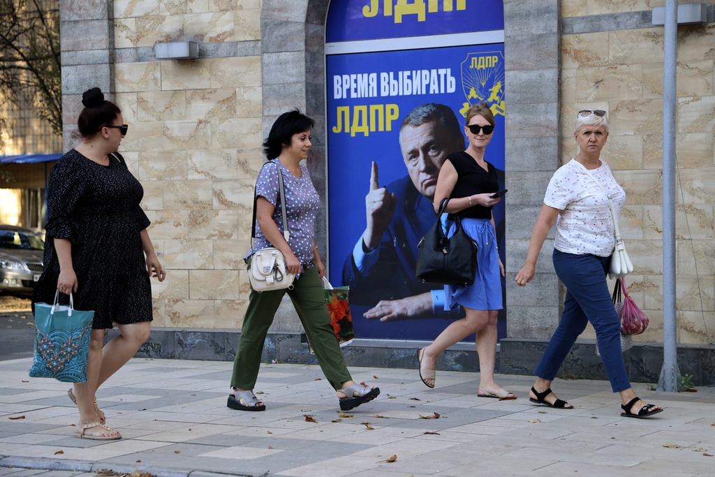 People walk past a Russian Liberal Democratic Party poster in Donetsk [AP]