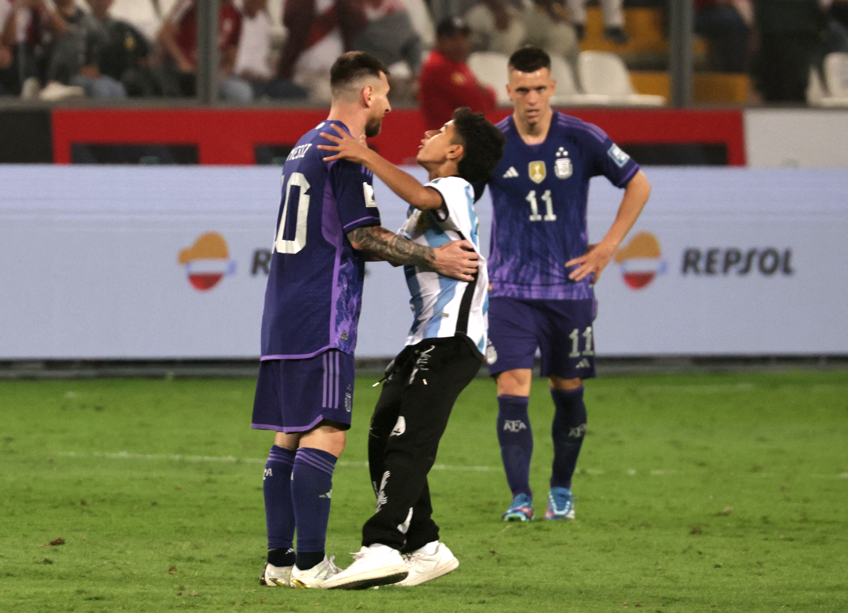 A fan runs on the pitch to hug Lionel Messi during the match at Estadio Nacional in Lima, Peru