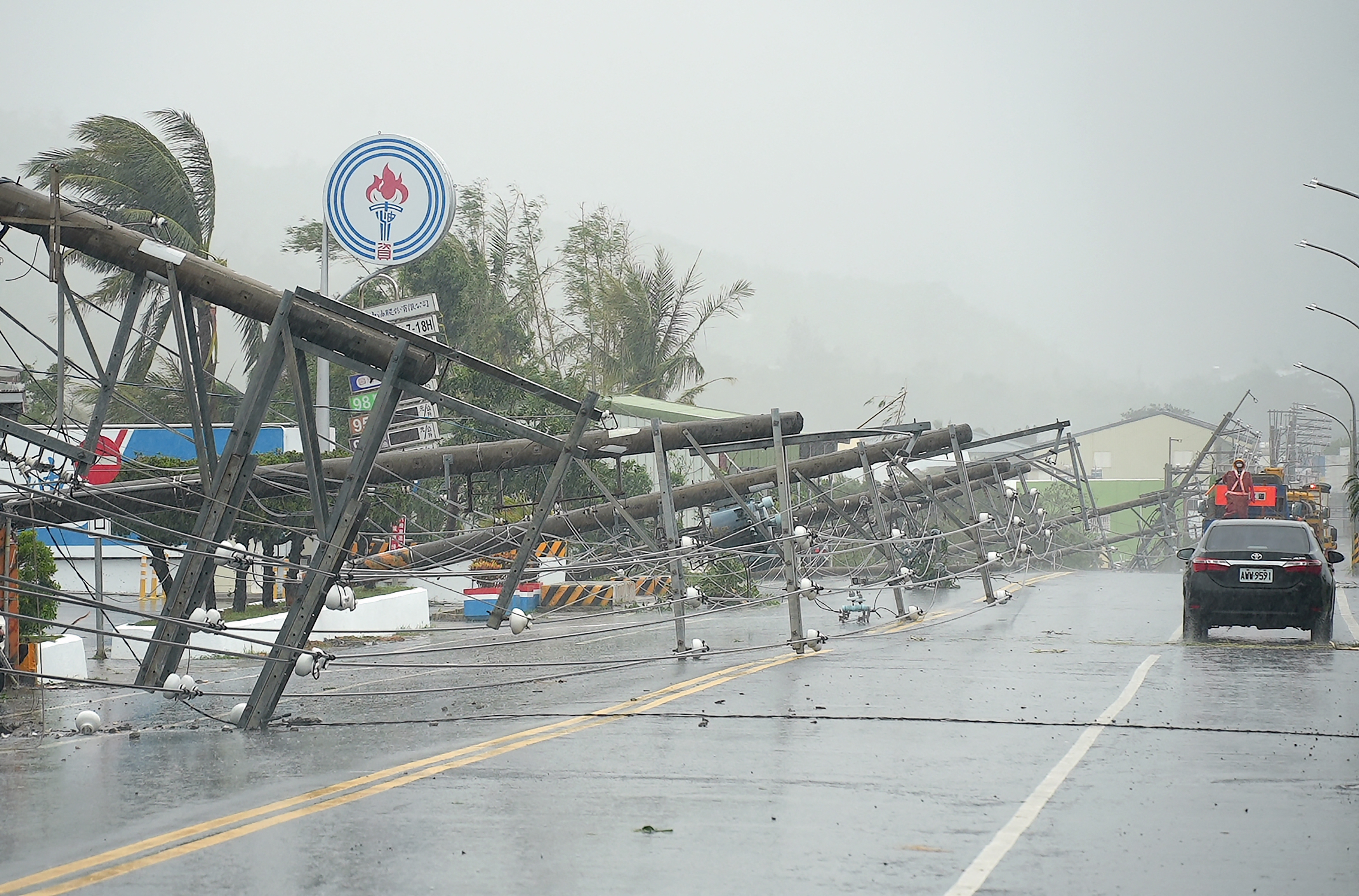 A car passes by power lines downed by the high winds from Typhoon Koinu in Taiwan's southern Pingtung County.