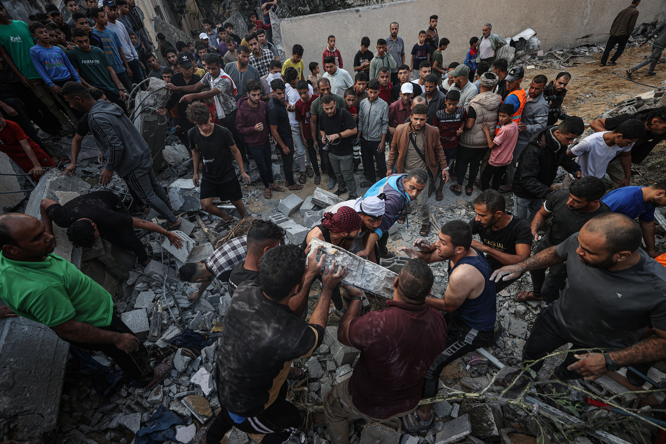 Civil defense members and residents conduct search and rescue operation amid rubble and destroyed buildings after Israeli attacks continue on the 11th day in Khan Yunis