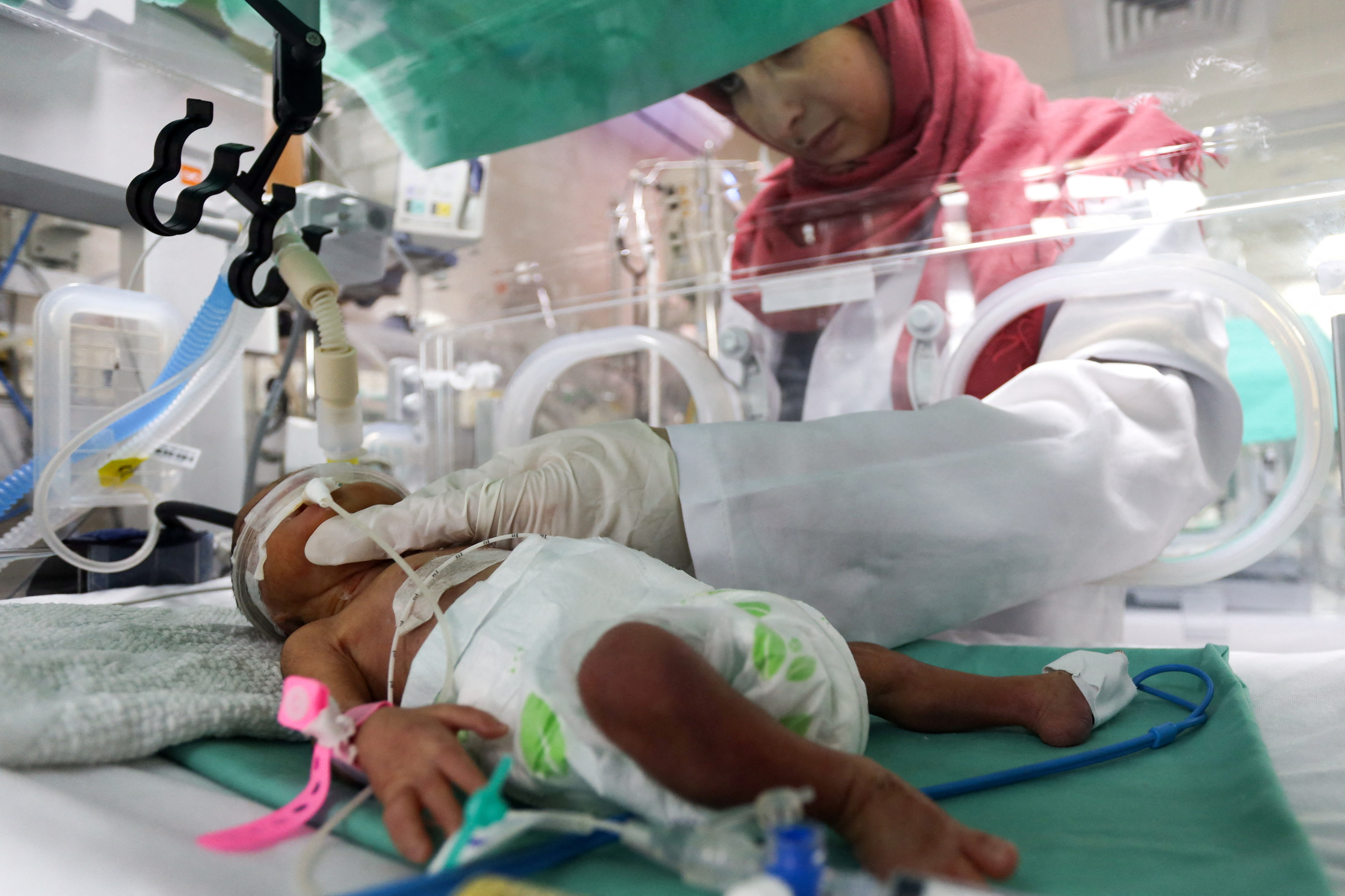 A medical worker assists a premature baby who lies in an incubator at the maternity ward of al-Shifa Hospital in Gaza City