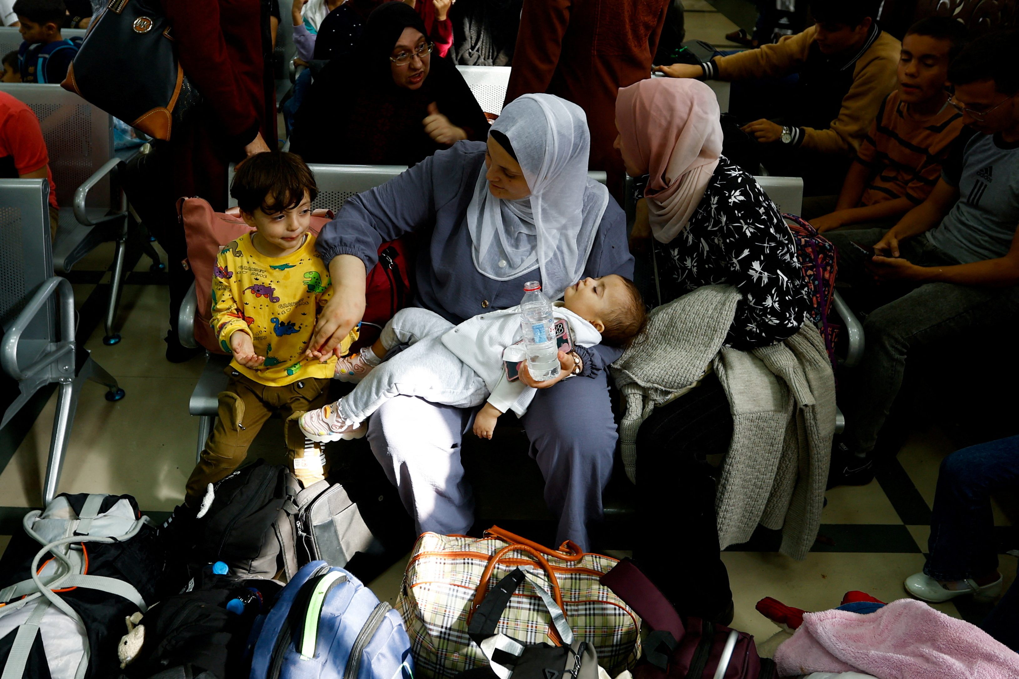 Palestinians with foreign passports wait for permission to leave Gaza, amid the ongoing conflict between Israel and Palestinian Islamist group Hamas, at the Rafah border crossing with Egypt, in Rafah in the southern Gaza Strip
