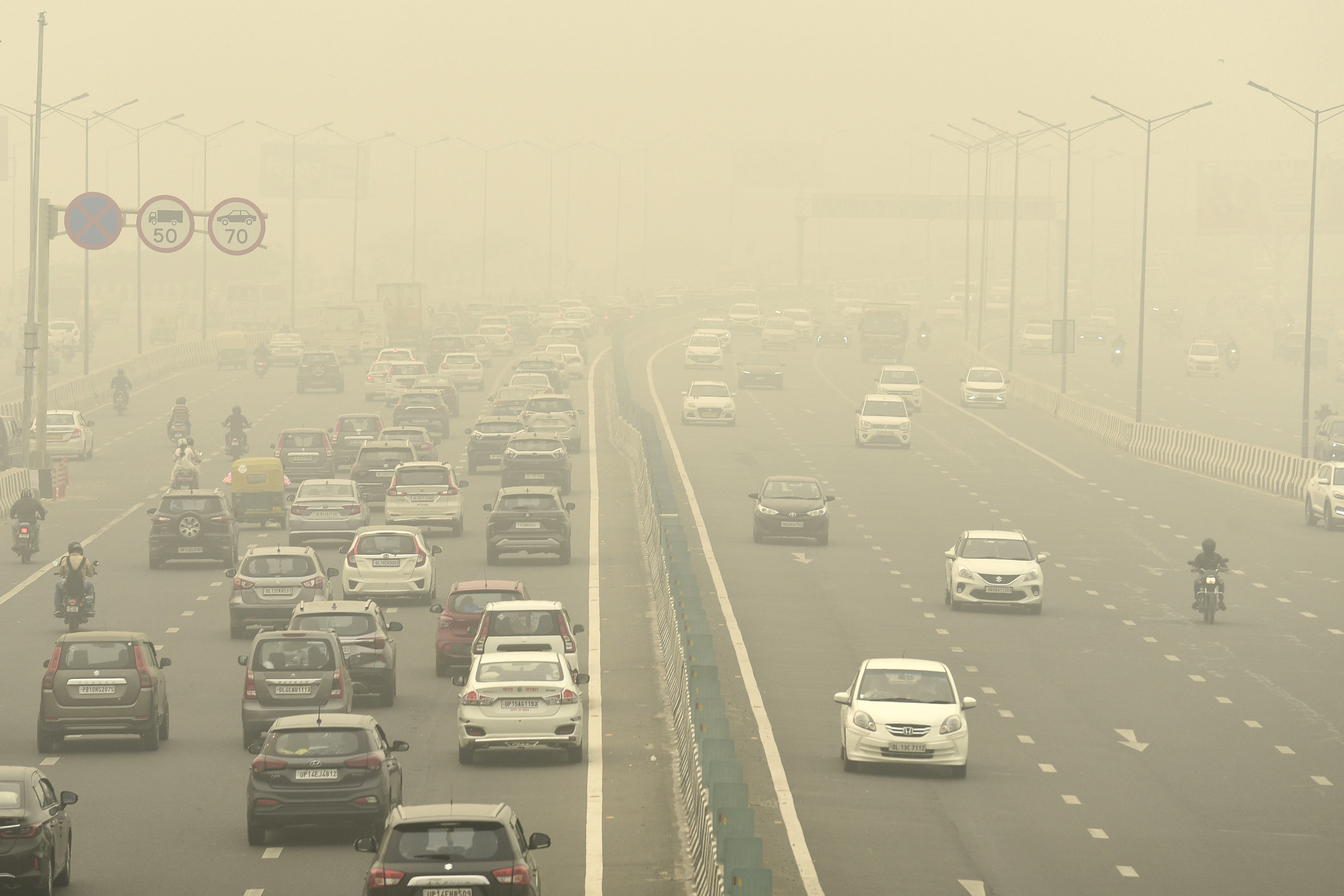 Traffic moves on a road enveloped by fog and smog in New Delhi, India