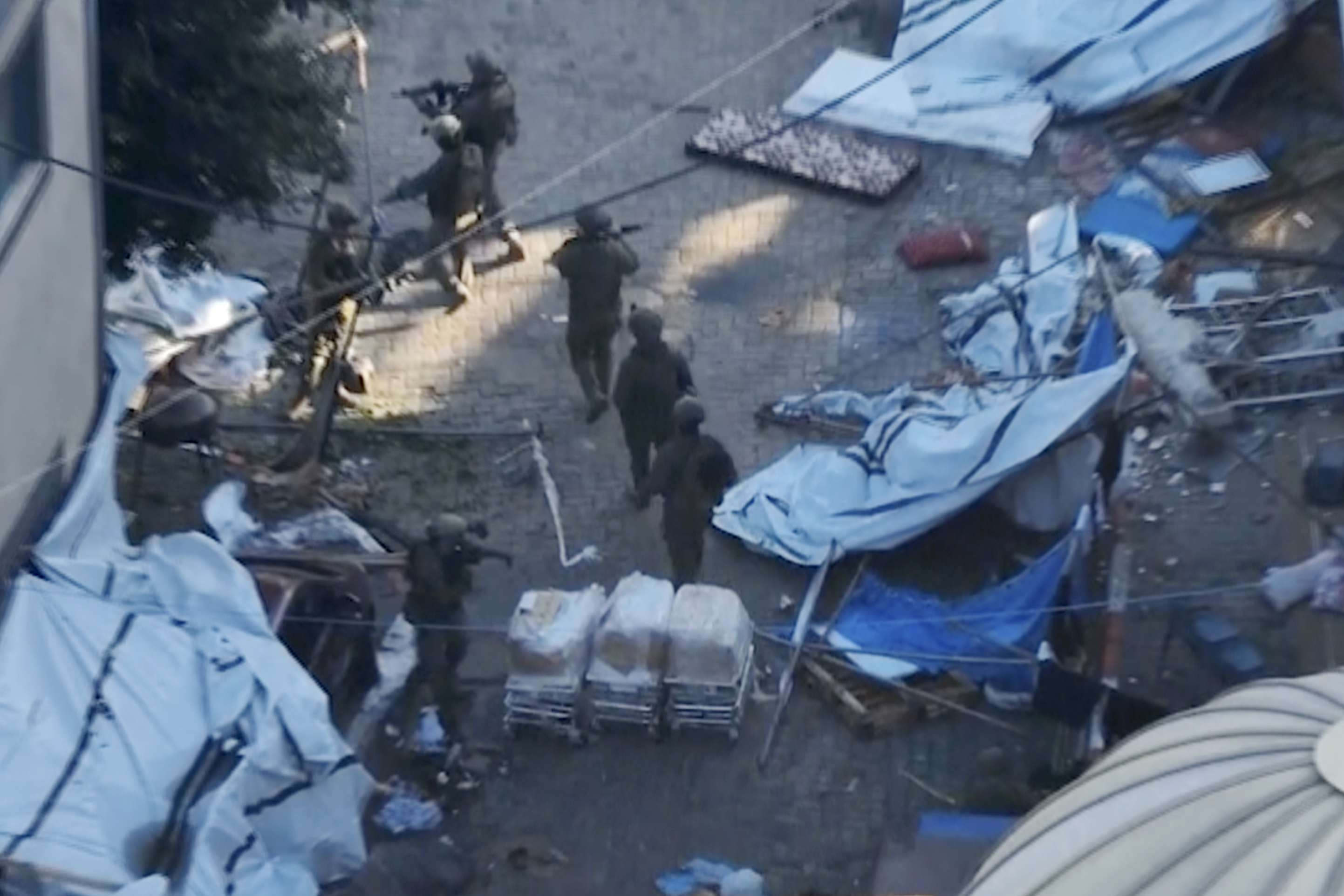 In this image taken from a video released by the Israeli Defense Forces on Tuesday, Nov. 15, 2023, Israeli soldiers walk in the area of Al-Shifa hospital in Gaza City.