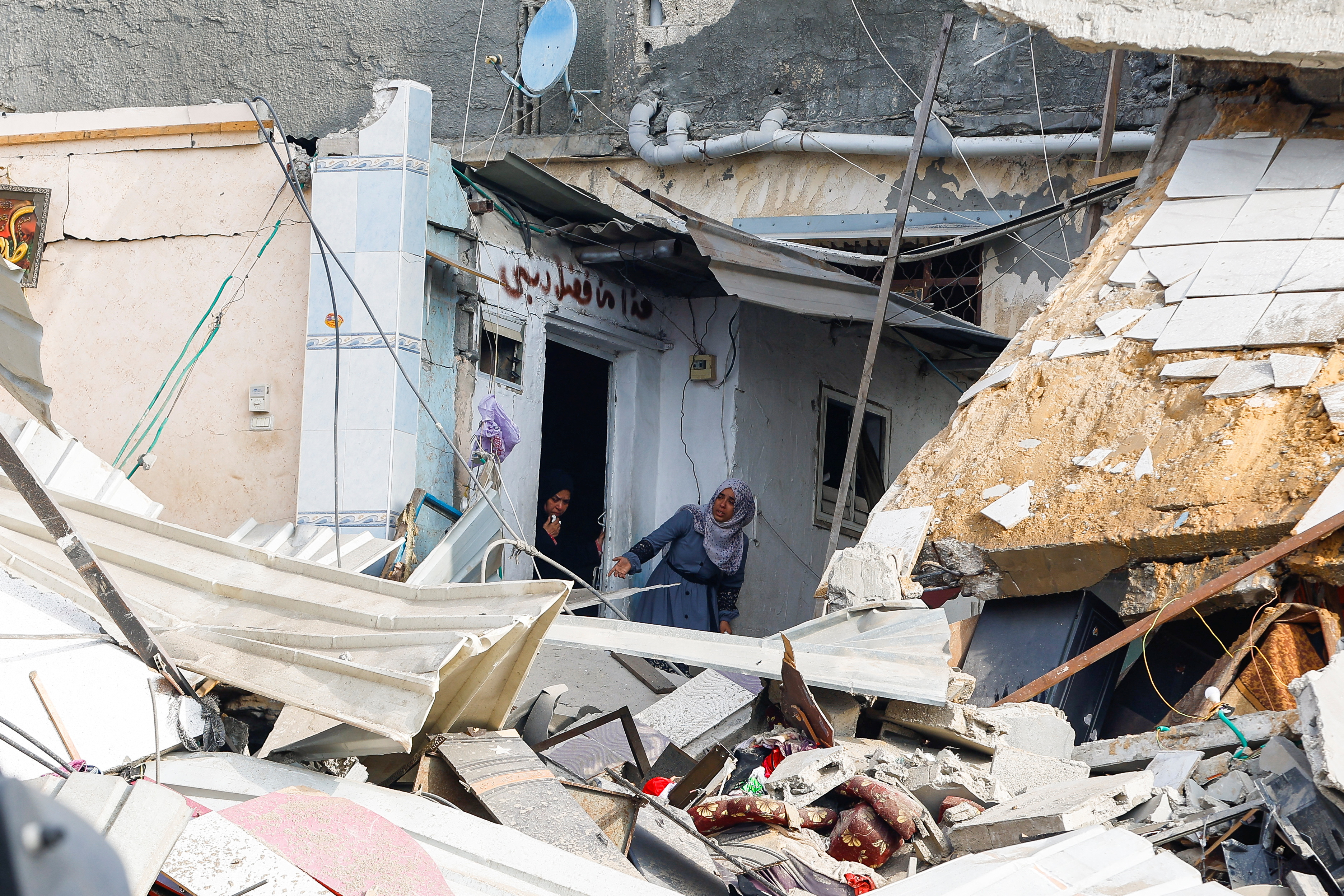 Palestinian women inspect the damage at the site of Israeli strikes on houses, amid the ongoing conflict between Israel and the Palestinian Islamist group Hamas, in Khan Younis in the southern Gaza Strip, December 12