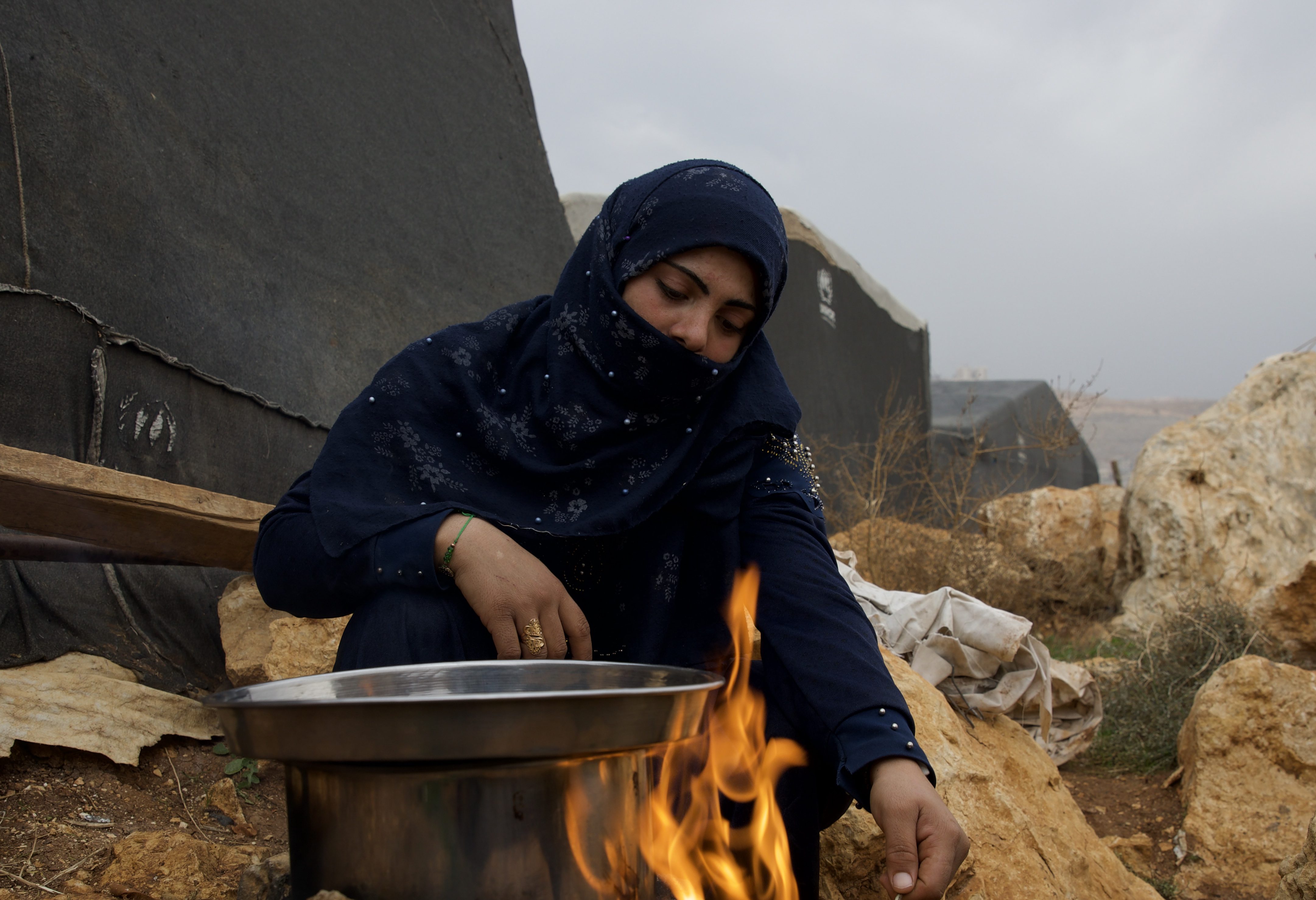 Yasmin Alhamou cooking over an open fire in a displacement camp