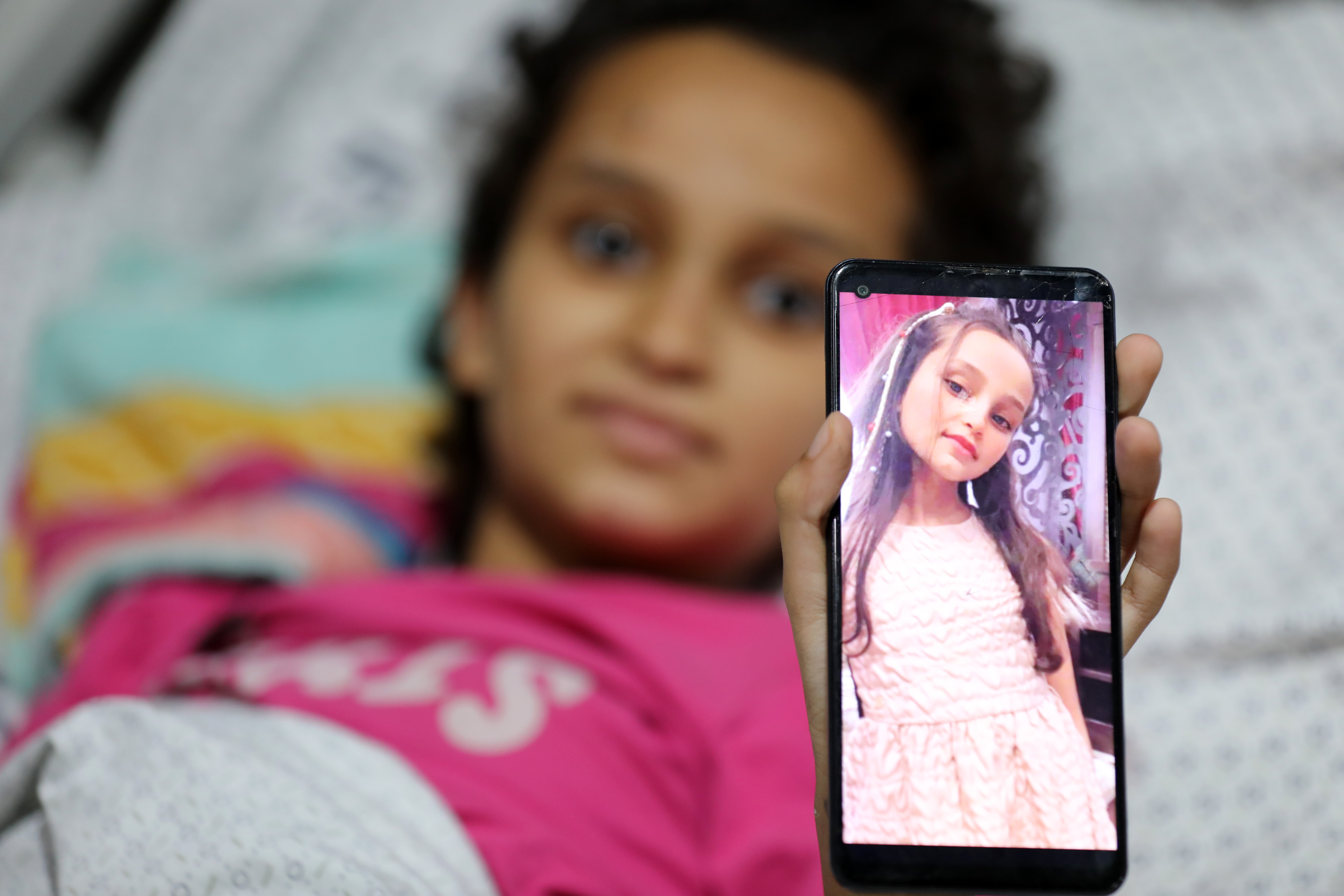 Twelve-year-old Mayar Abu Saad shows off a photo of herself before the war with long hair