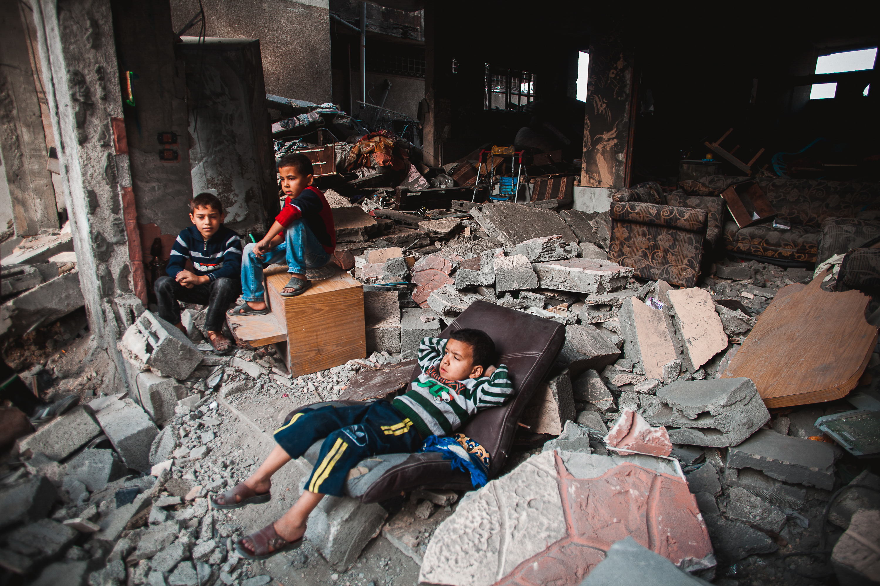 1- Baraa Azam is lying in front of the rubble of his home after an Israeli airstrike flattened the residence in the Al Zaitoun vicinity in Gaza City. Baraa was injured during the air strike.
