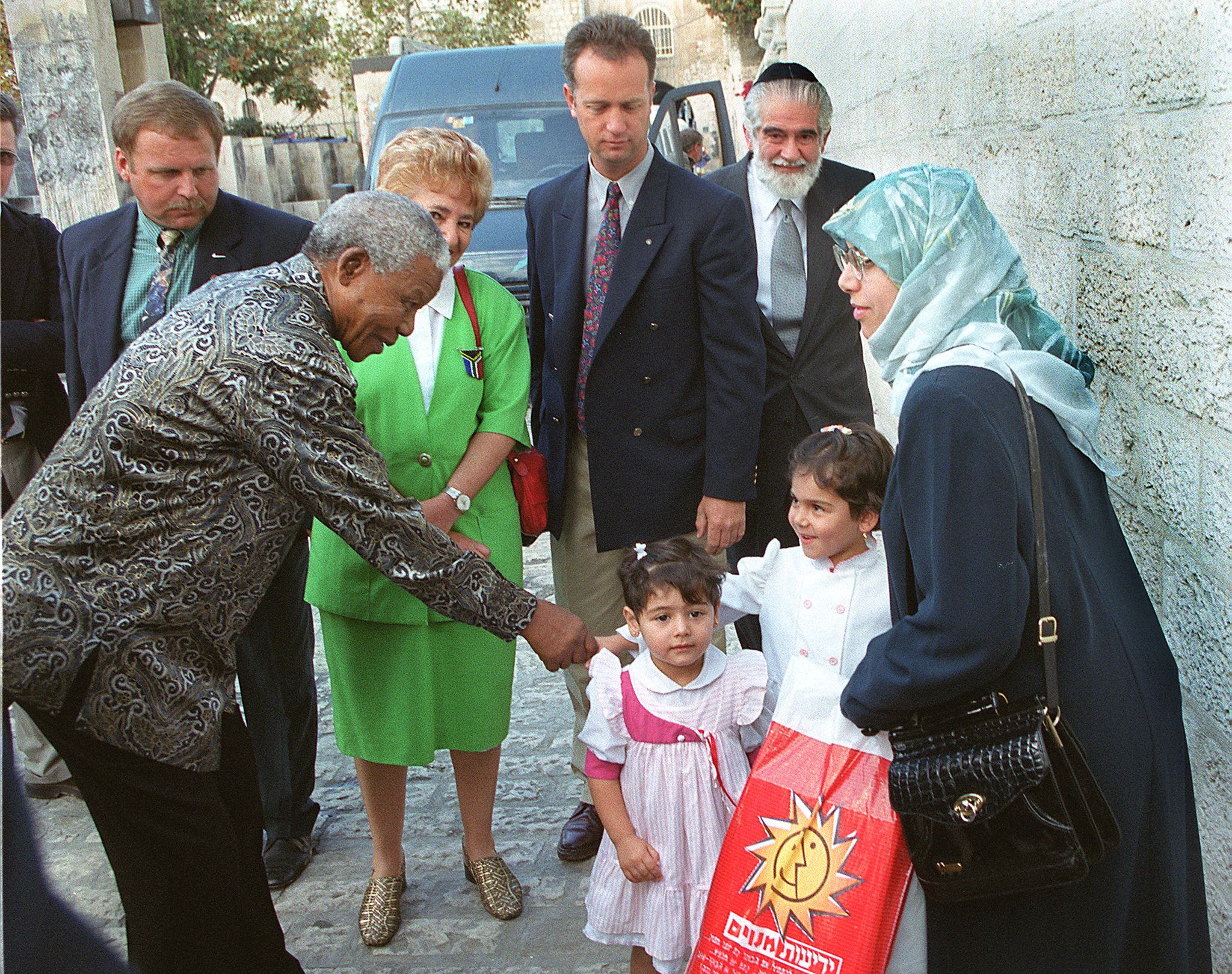 Former South African President Mandela shakes hands with a young Palestinian girl during a tour of Jerusalem’s old city in October 1999