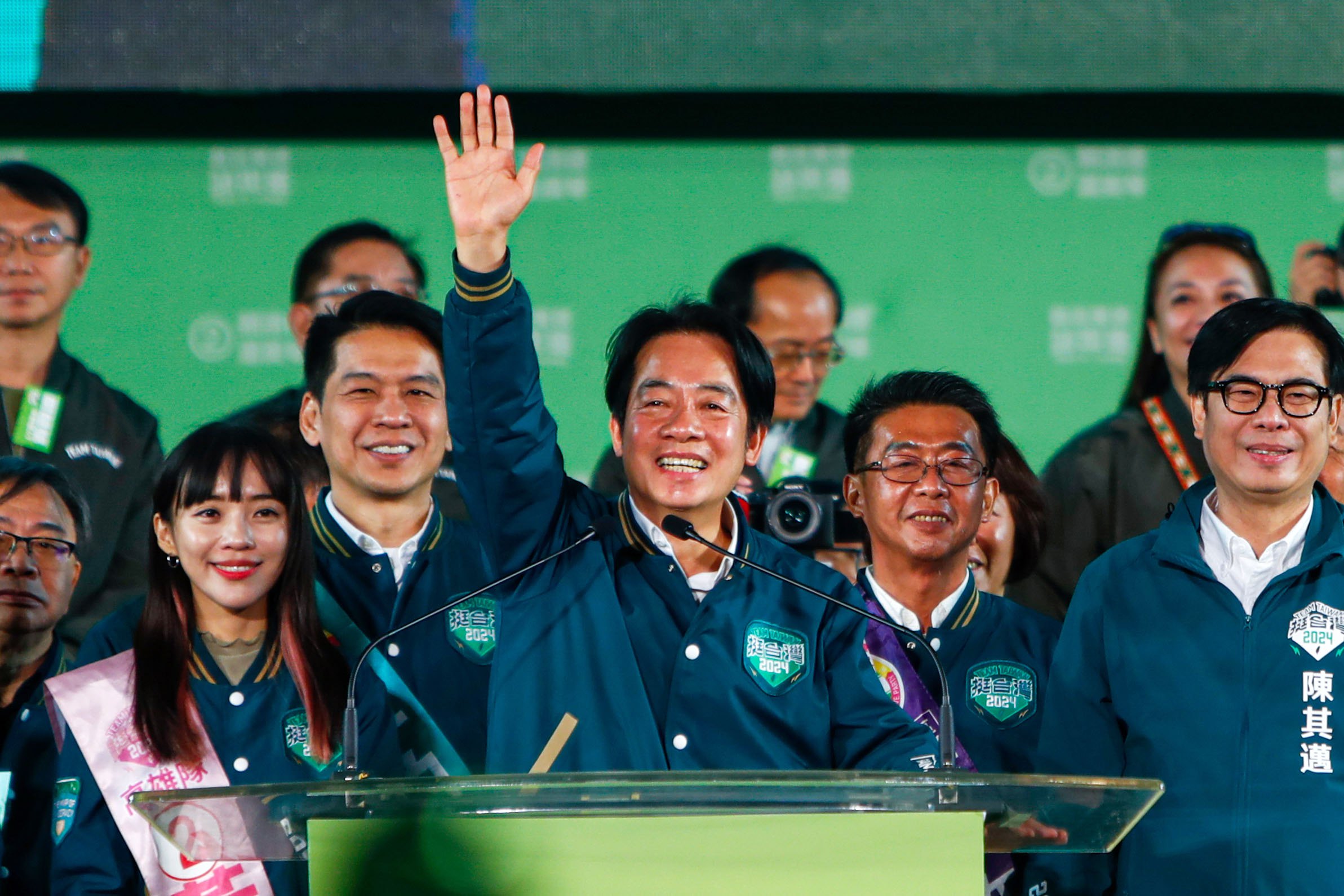 William Lai, the DPP presidential candidate. Hs is standing on a stage and is wearing the green of his party. He is acknowledging the crowd.