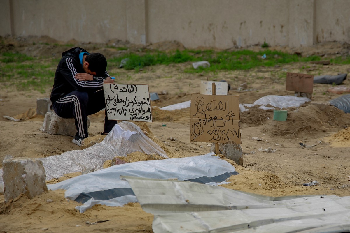 A young man sits by the shallow tomb