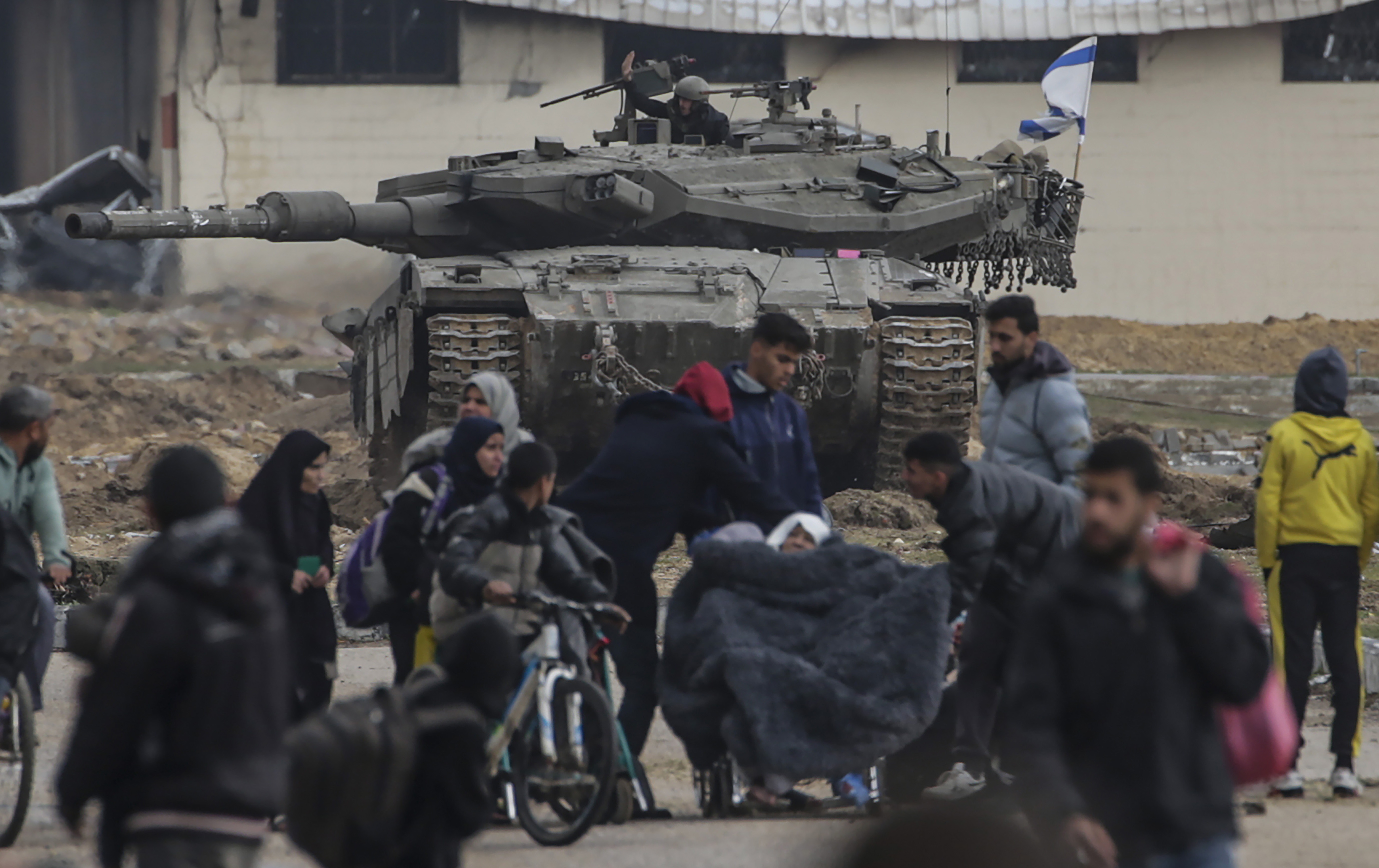 epa11109089 Internally displaced Palestinians move past Israeli tanks after the Israeli army told residents of Khan Yunis camp to leave their homes and head towards Rafah camps near the Egyptian border, southern Gaza Strip, 27 January