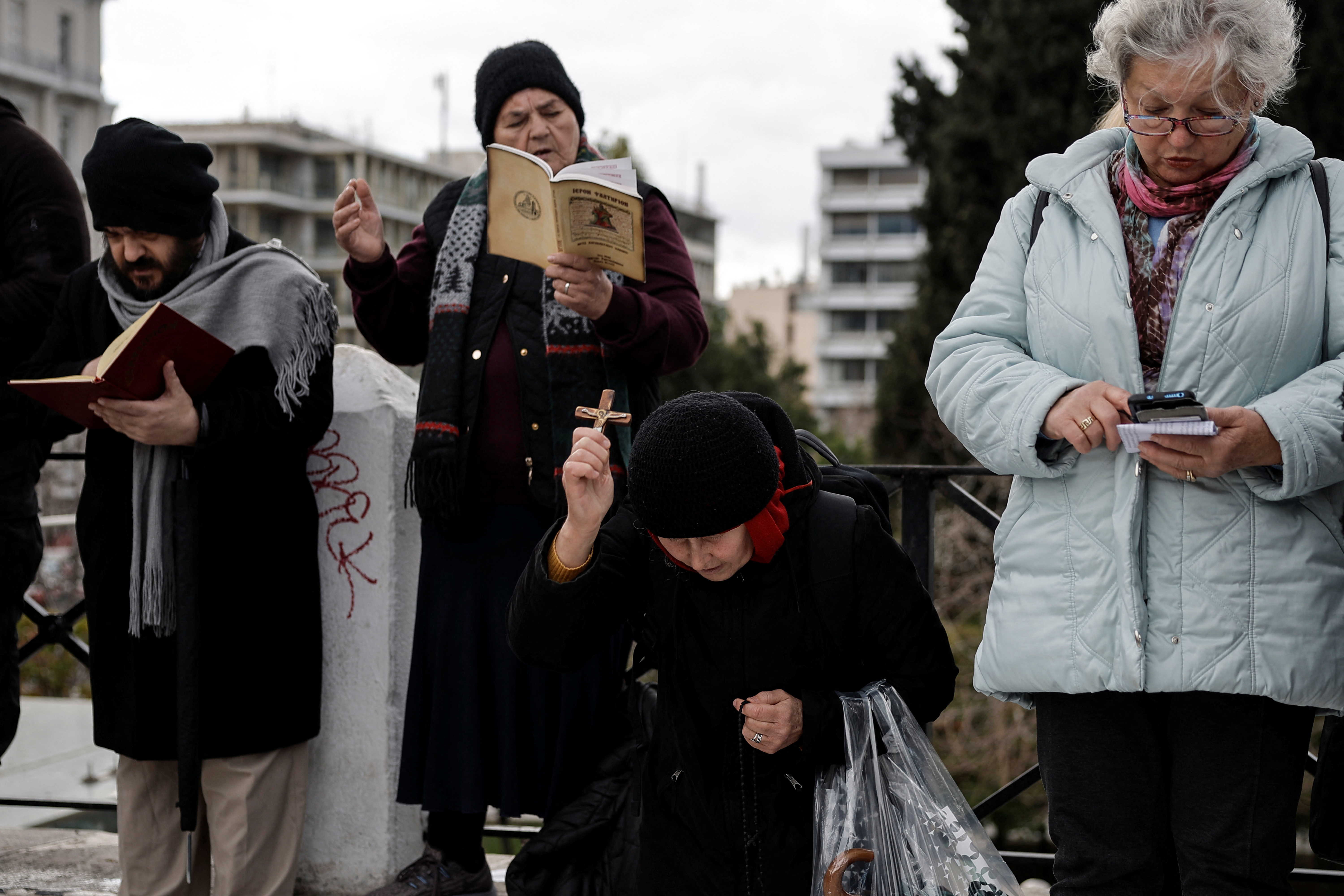 Protesters against the bill pray in front of the Greek parliament, ahead of the vote, in Athens