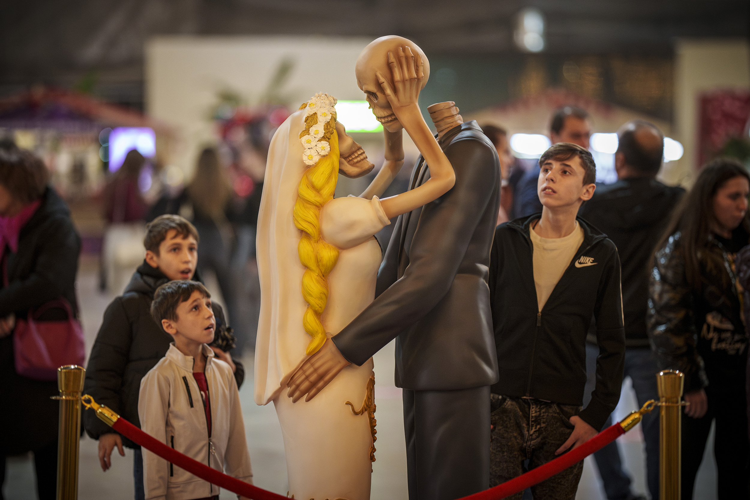 People look at a skeleton couple kissing installation dubbed " 'Till Death Do Us Part" during a Valentine's Day event in Bucharest, Romania, Tuesday, Feb. 13