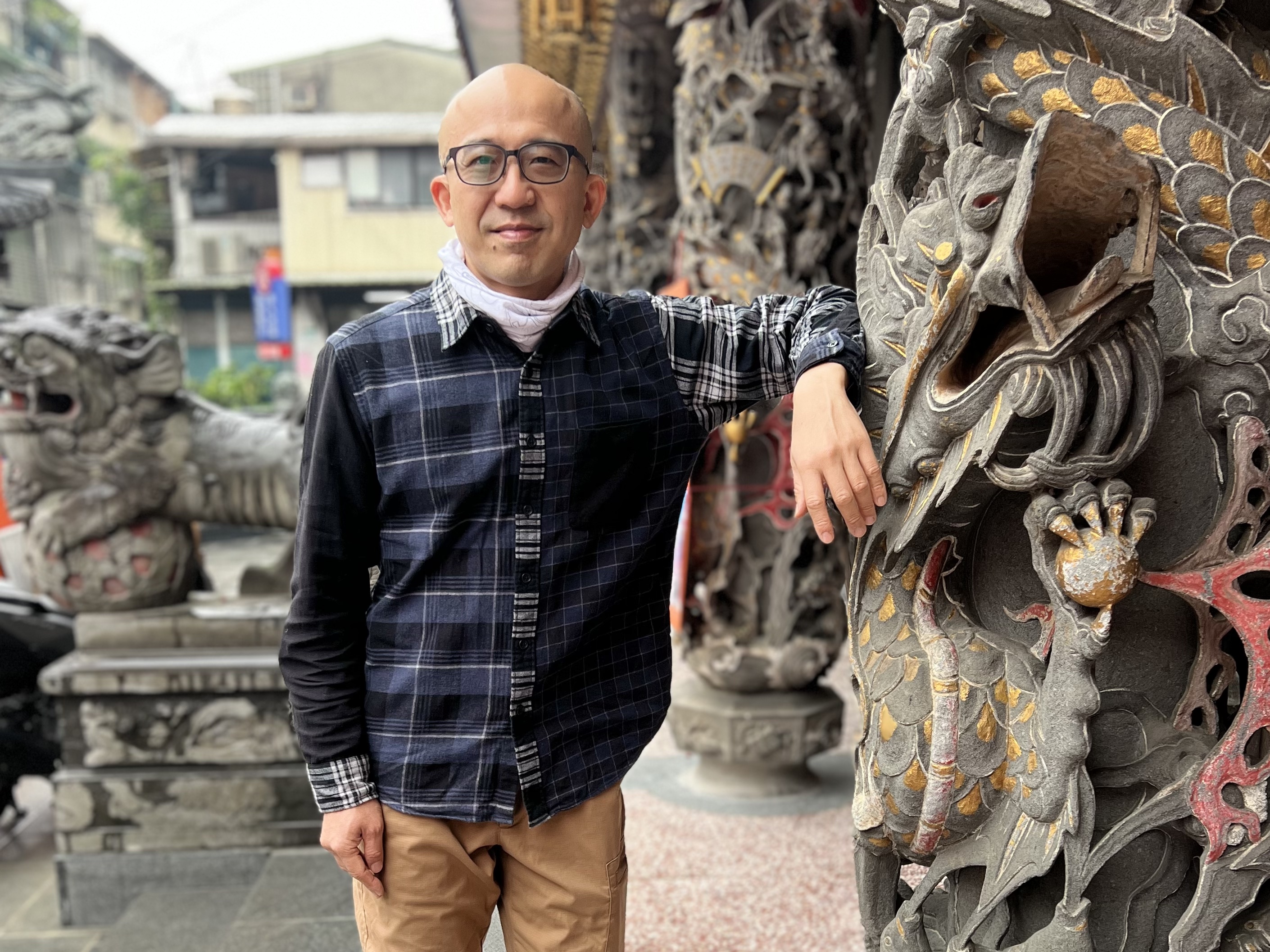 IHua Wu, born in a Year of the Dragon, stands next to a statue of his zodiac animal at a temple in Taipei, Taiwan